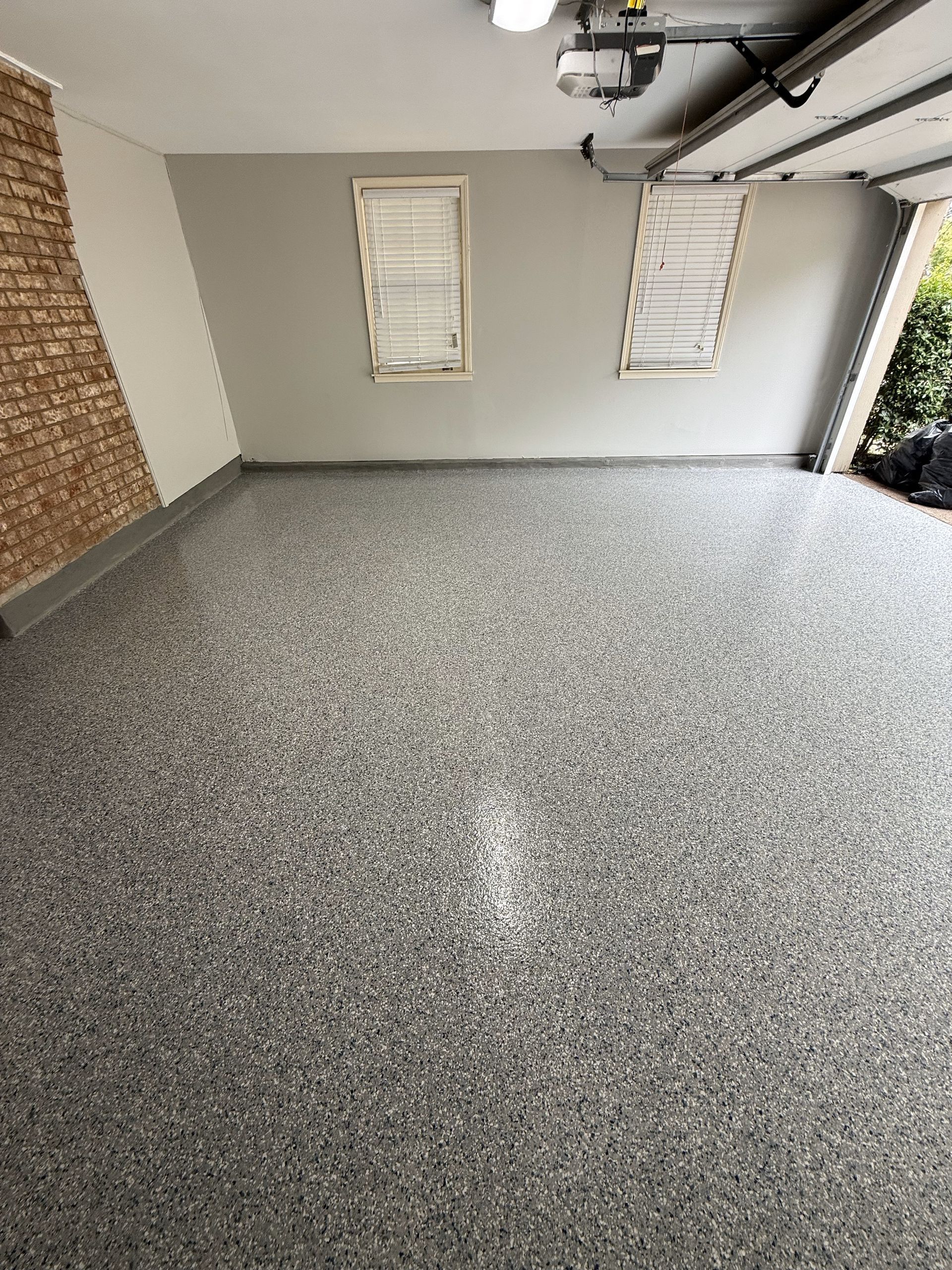 A garage with a gray floor and a brick wall.
