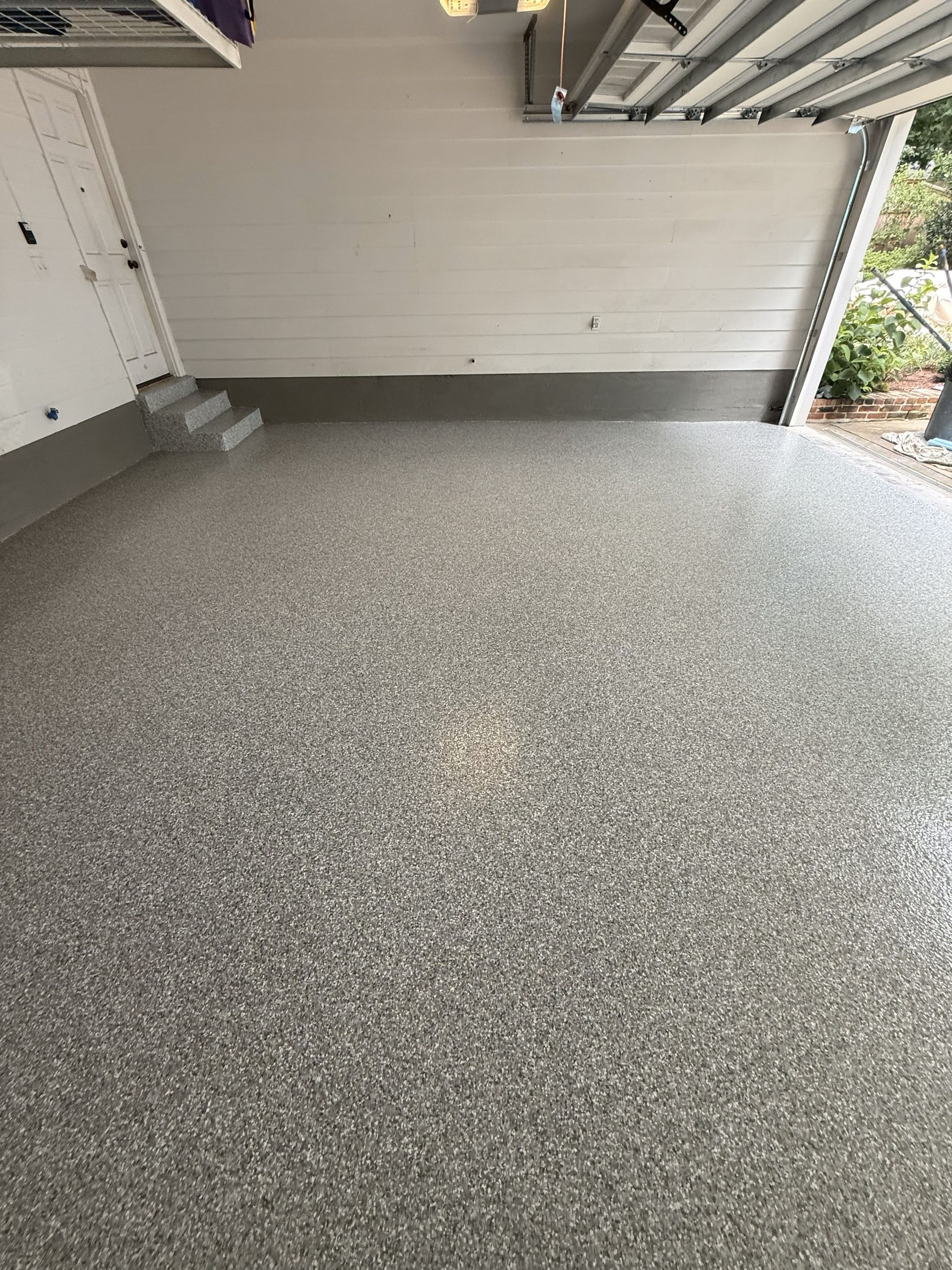 A newly coated garage floor with gray and white speckled epoxy.
