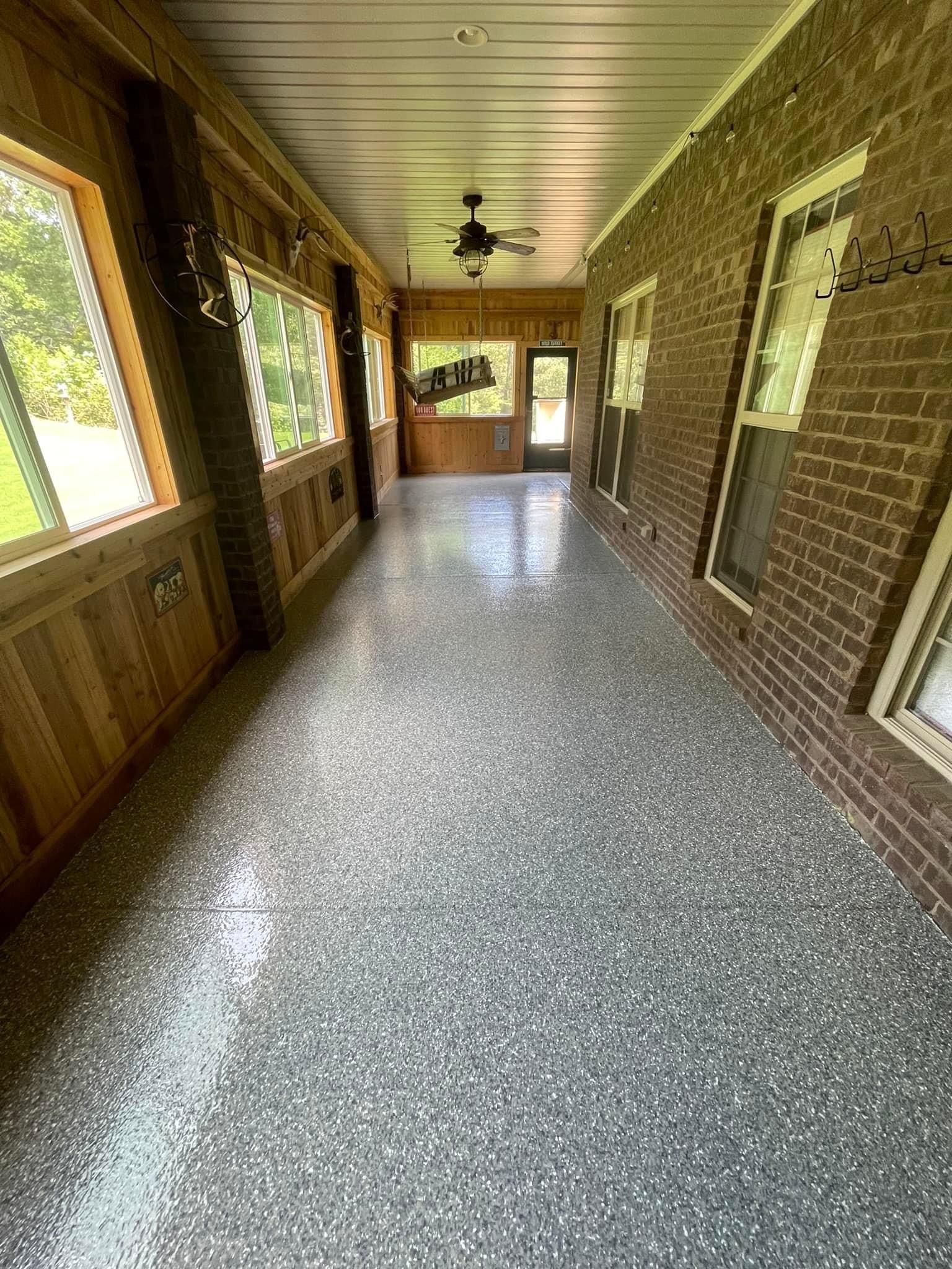 A long hallway with a ceiling fan and a brick wall.