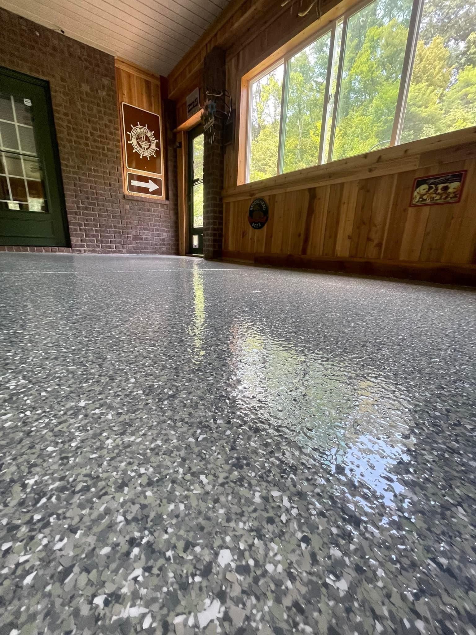 A room with a gray floor and a large window.