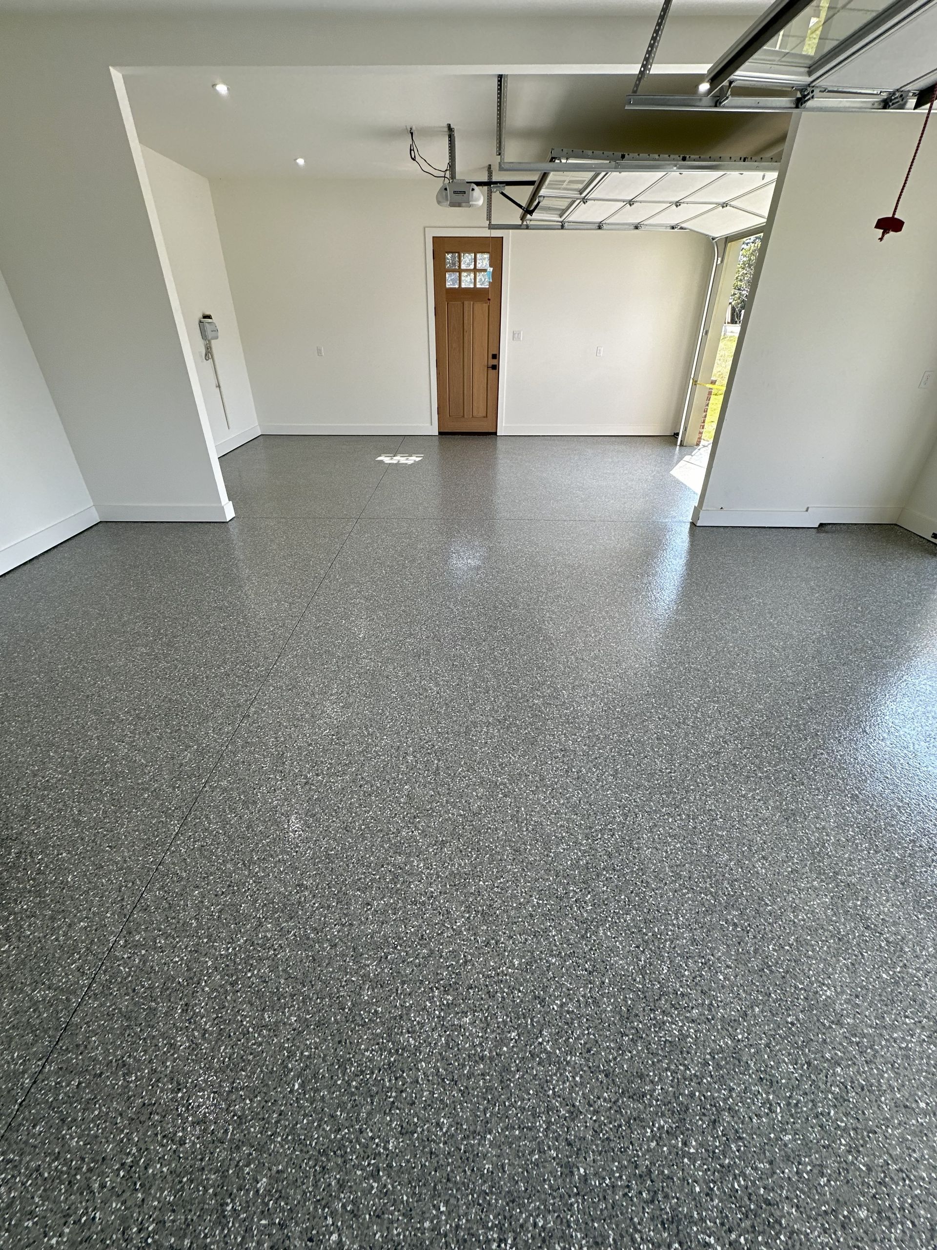 Garage with glossy gray speckled floor, white walls, and a wooden door.