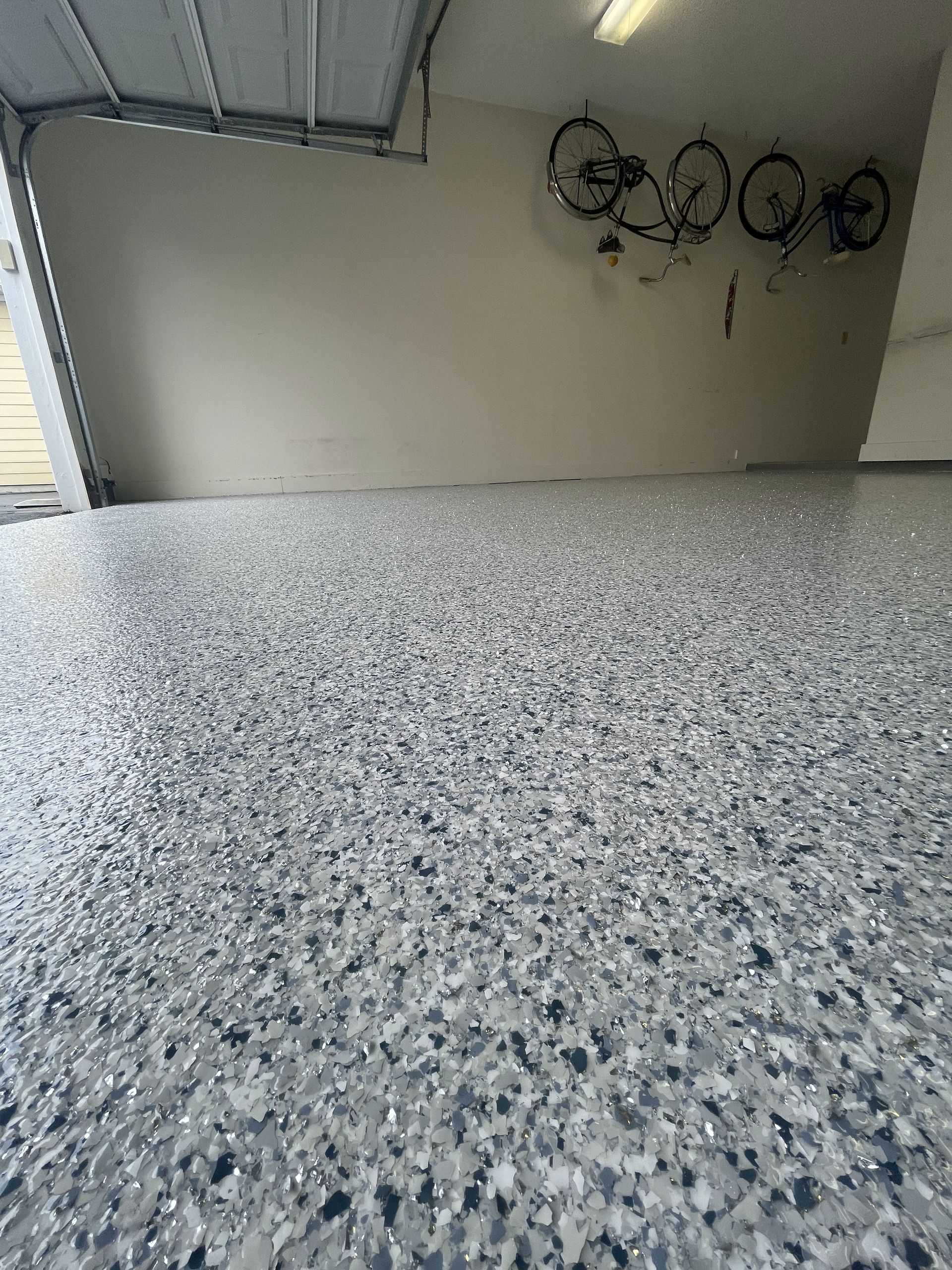 A garage with a concrete floor and bikes hanging on the wall.