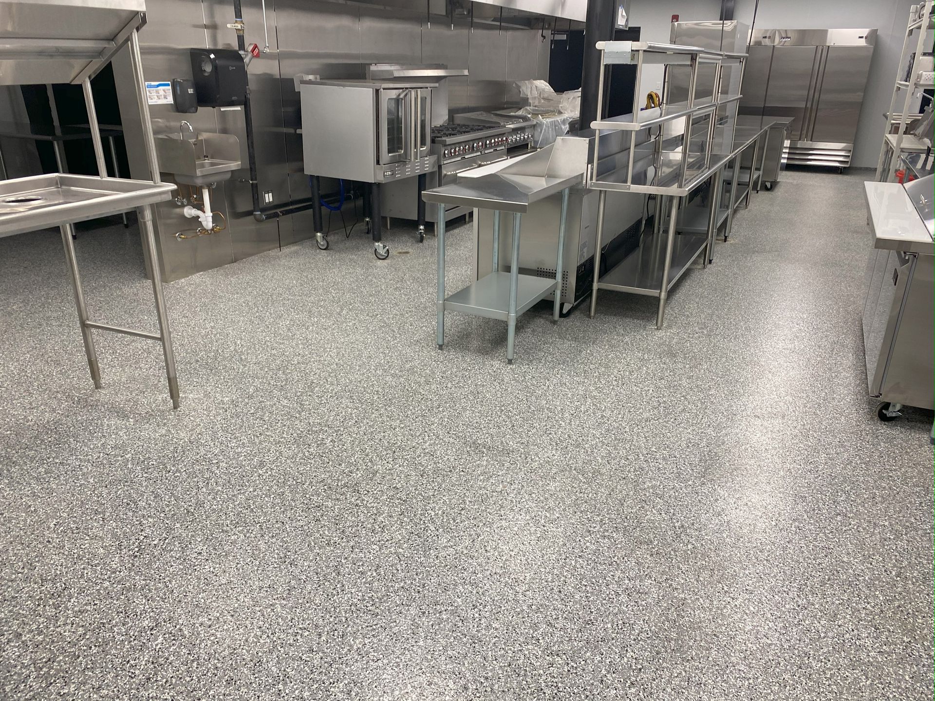 A large kitchen with stainless steel appliances and a gray floor.