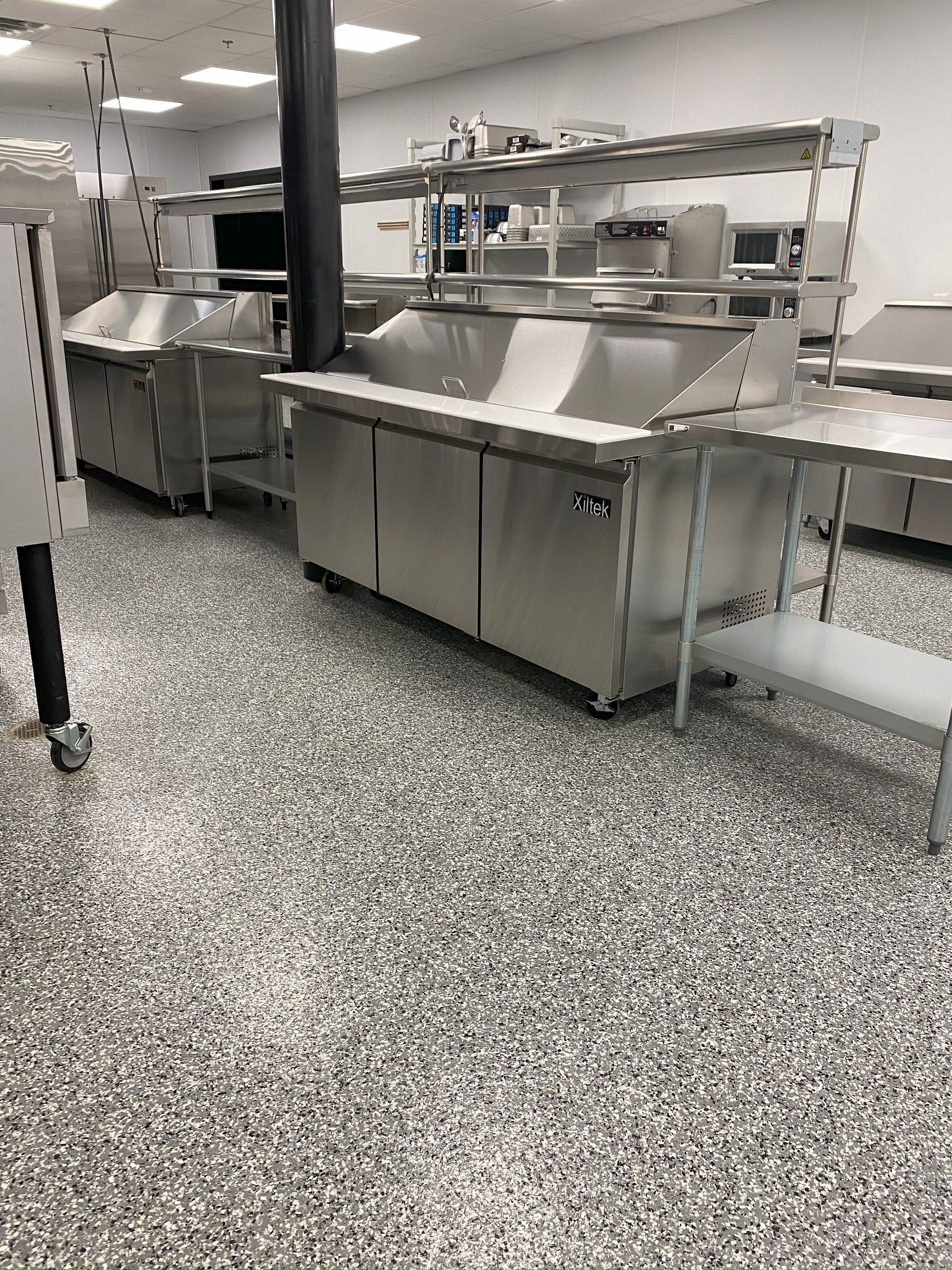 A kitchen with stainless steel appliances and a gray floor.