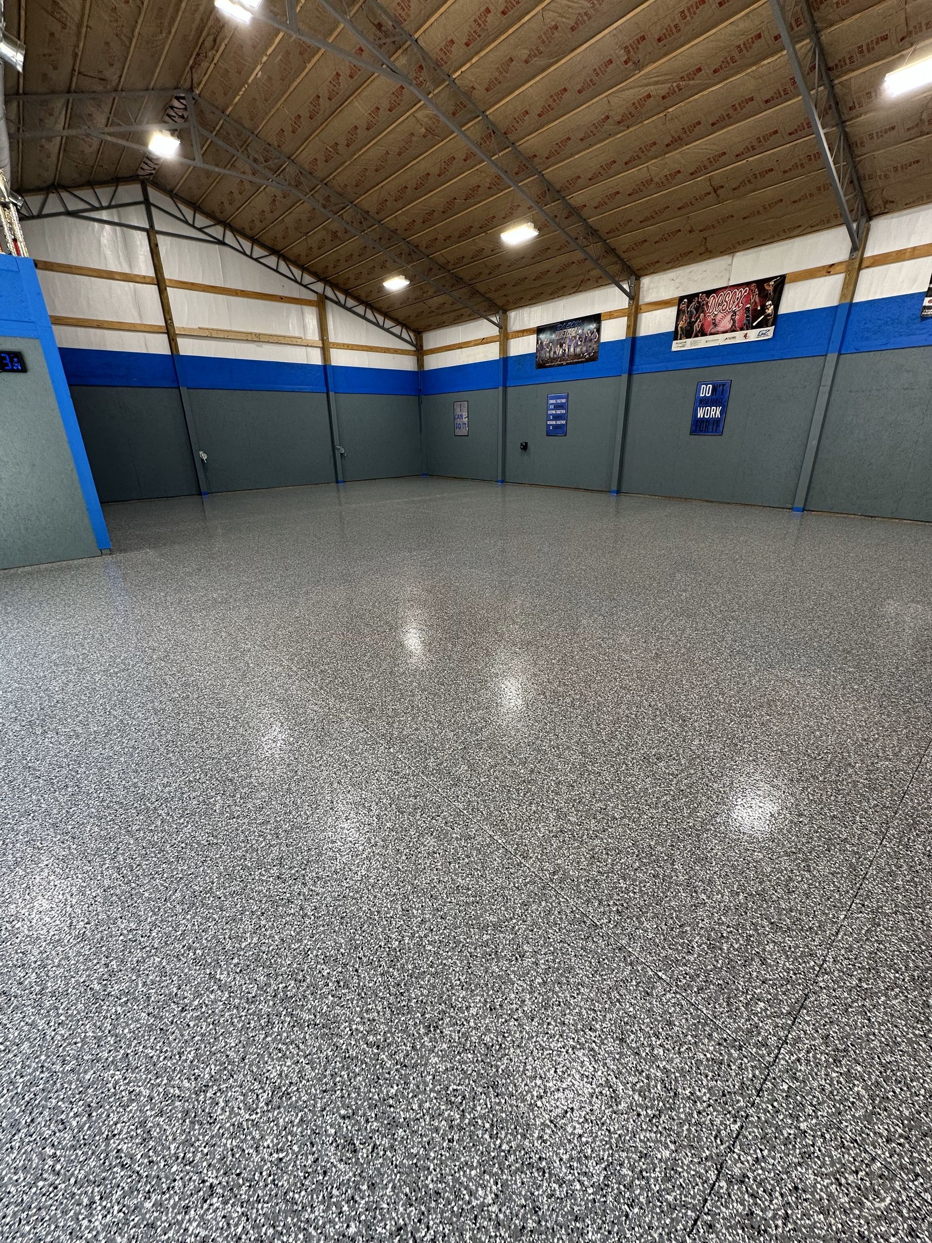 A large room with a gray and blue floor and a wooden ceiling.