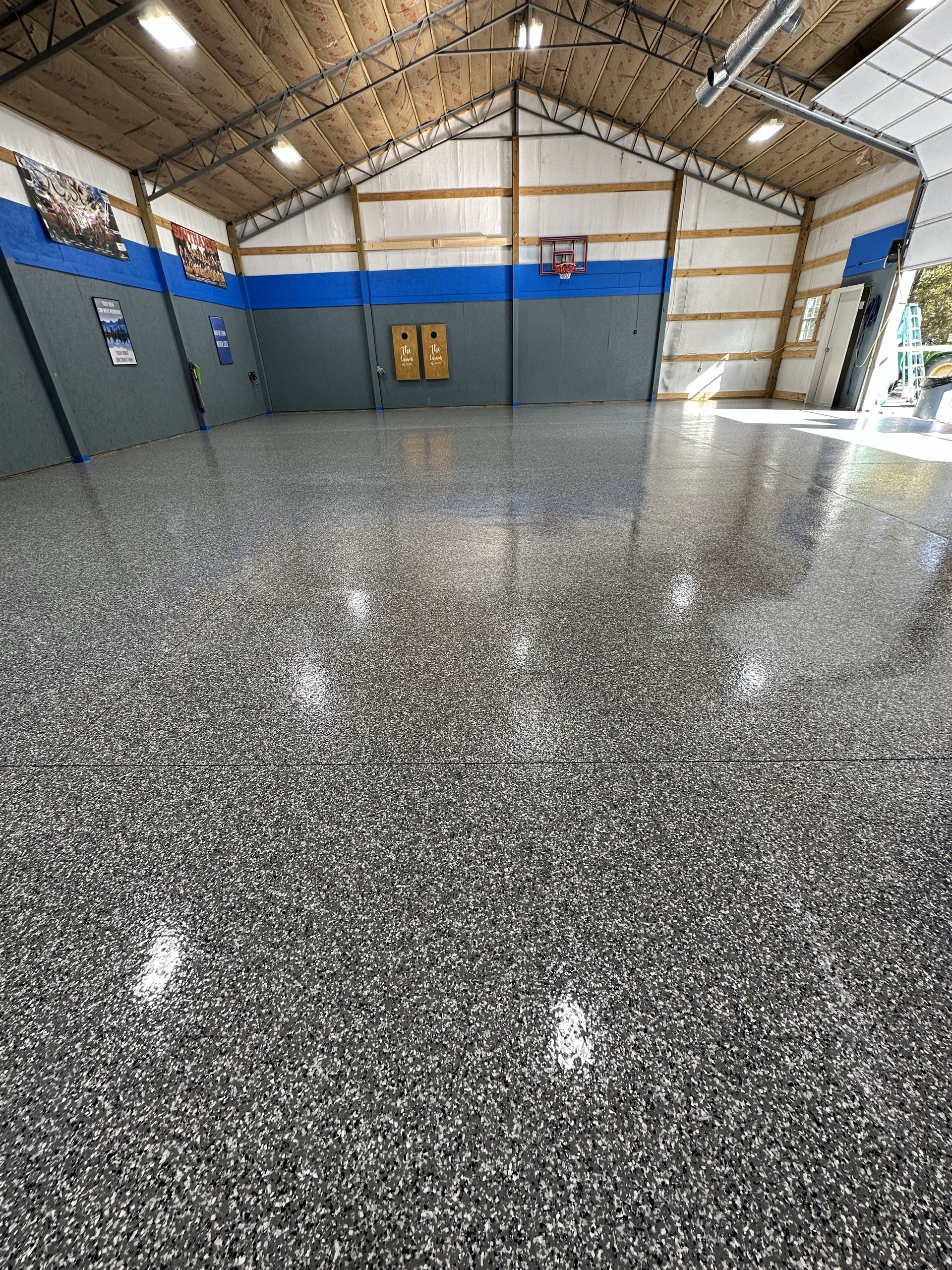 A large room with a shiny floor and a basketball hoop in the background.