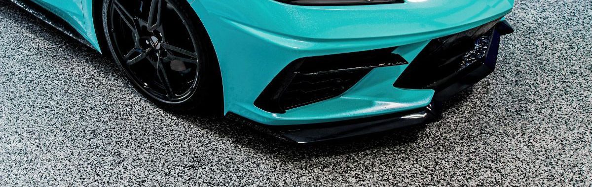 A blue sports car is parked on a gravel road.