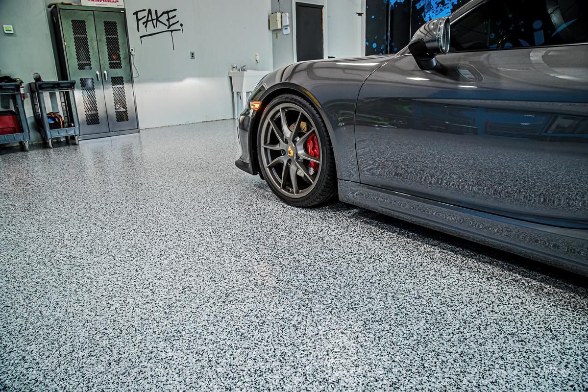Dark gray sports car in a window tinting shop with epoxy garage floor