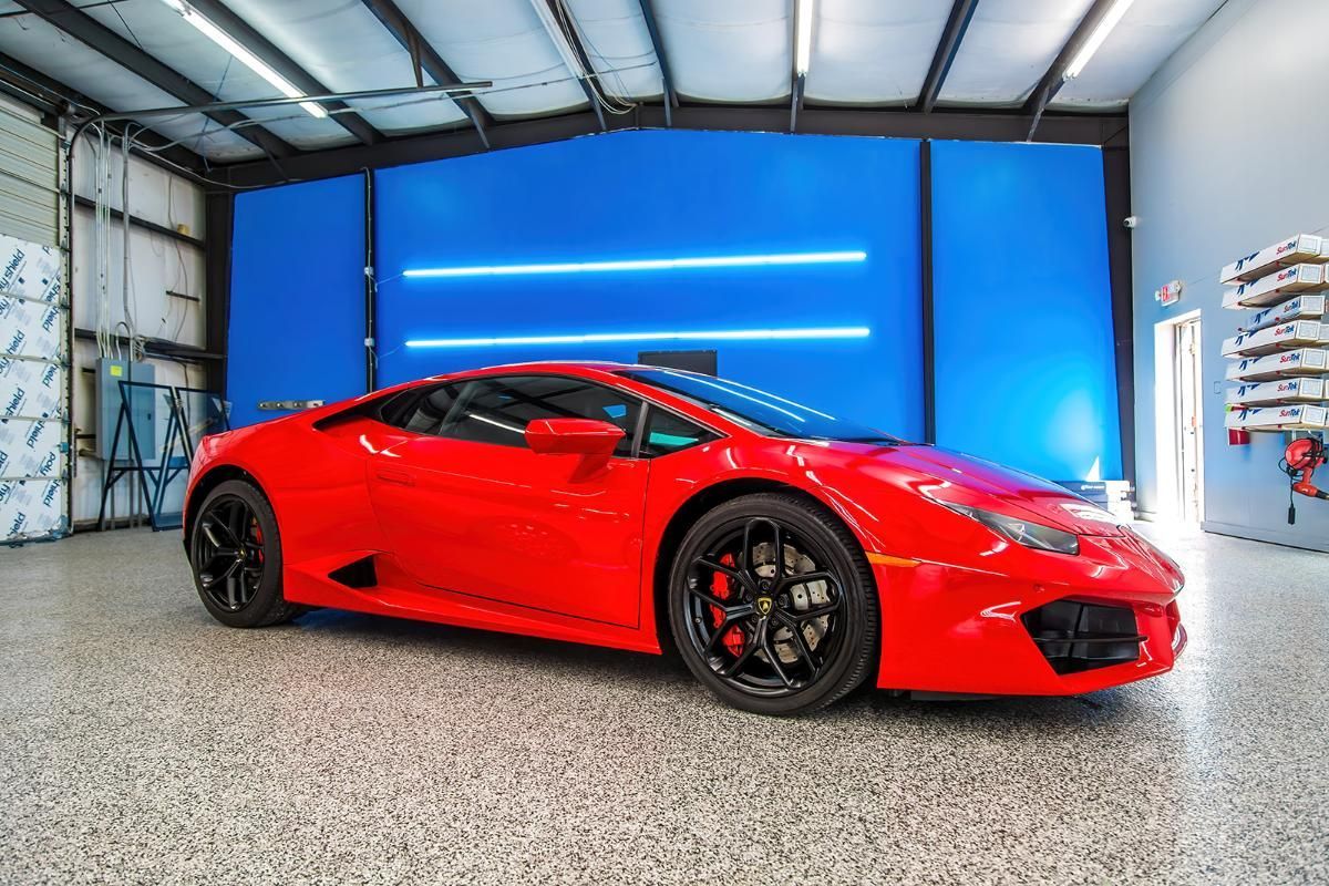 Red sports car in a window tinting shop with epoxy garage floor