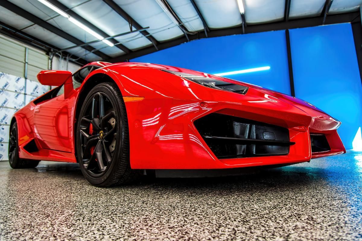 Red sports car in a window tinting shop with epoxy garage floor