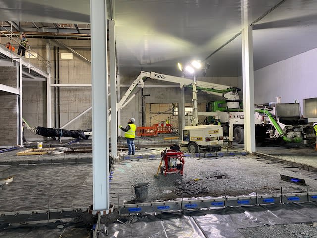 Concrete being poured into a warehouse to make a new floor