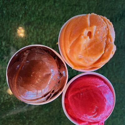 Three cups of different flavors of ice cream are sitting on a table. Three cups of different flavors of ice cream are sitting on a table.