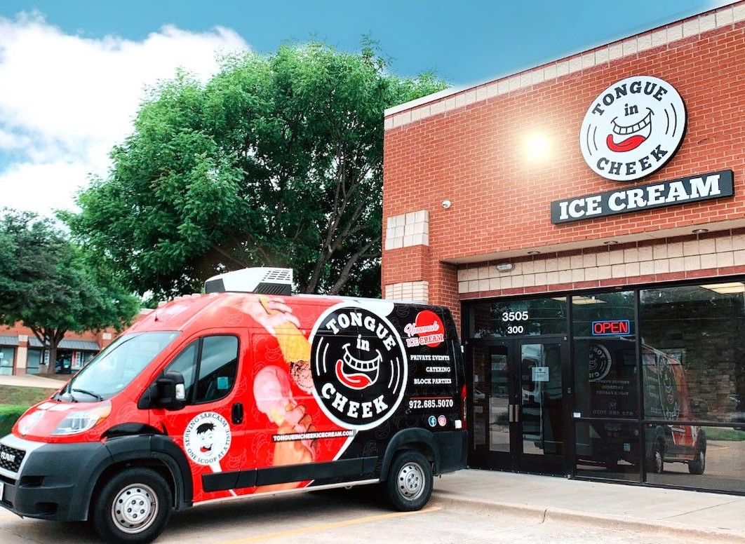 A red van is parked in front of an ice cream shop.