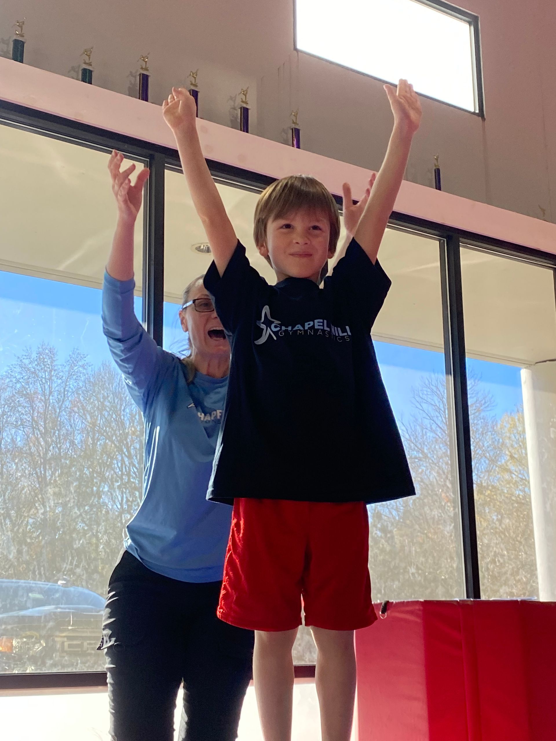 A woman is helping a young boy balance on a balance beam.