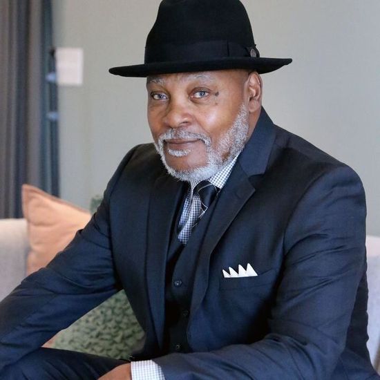 A man in a suit and hat is sitting on a couch