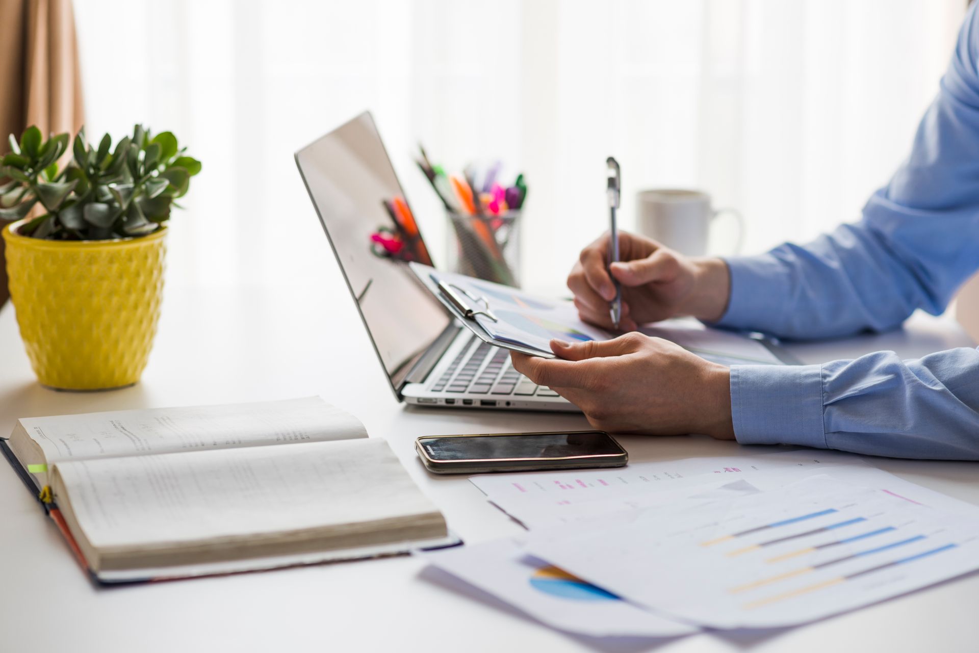 A man is sitting at a desk with a laptop and papers.