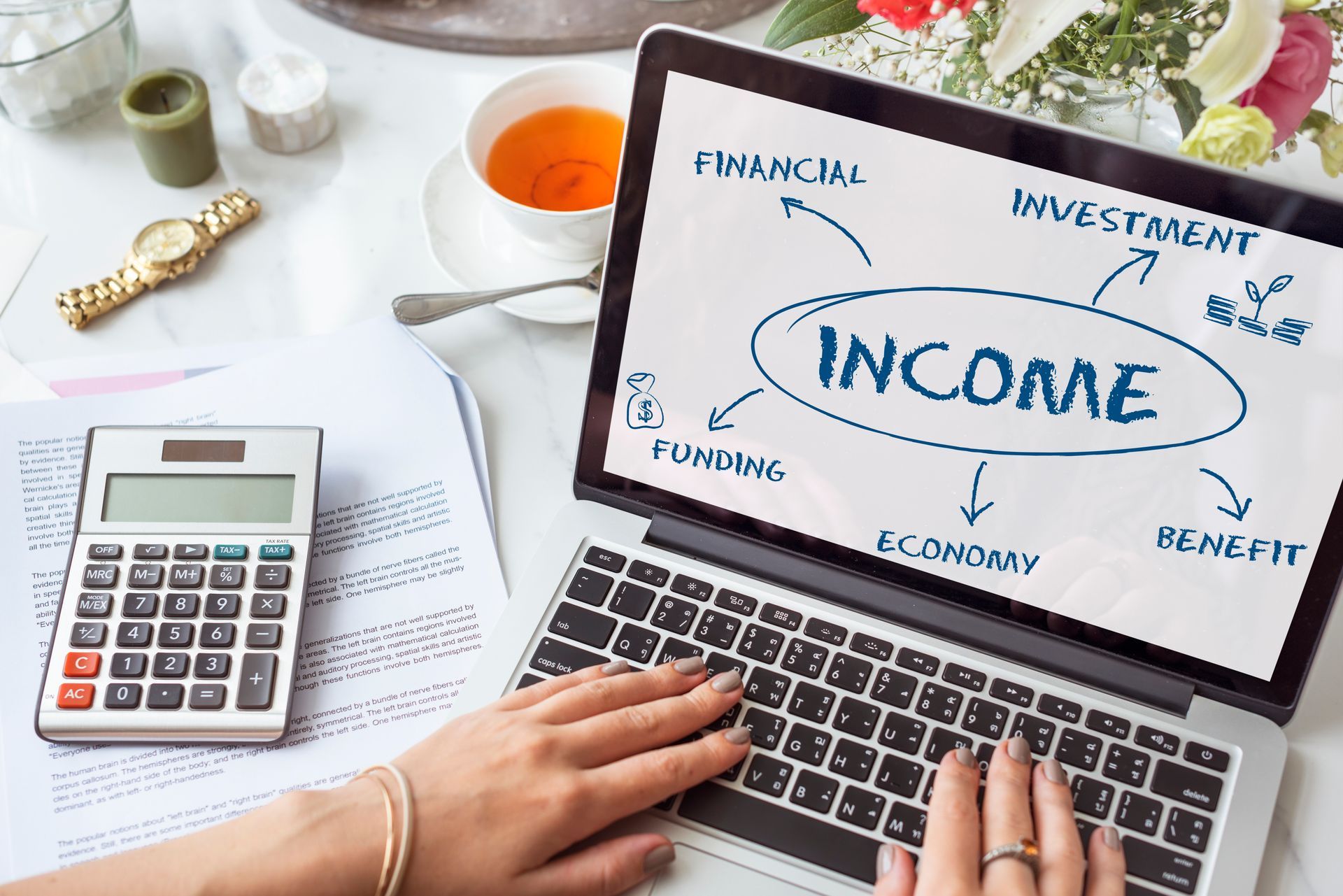 A woman is typing on a laptop computer with the word income written on the screen.
