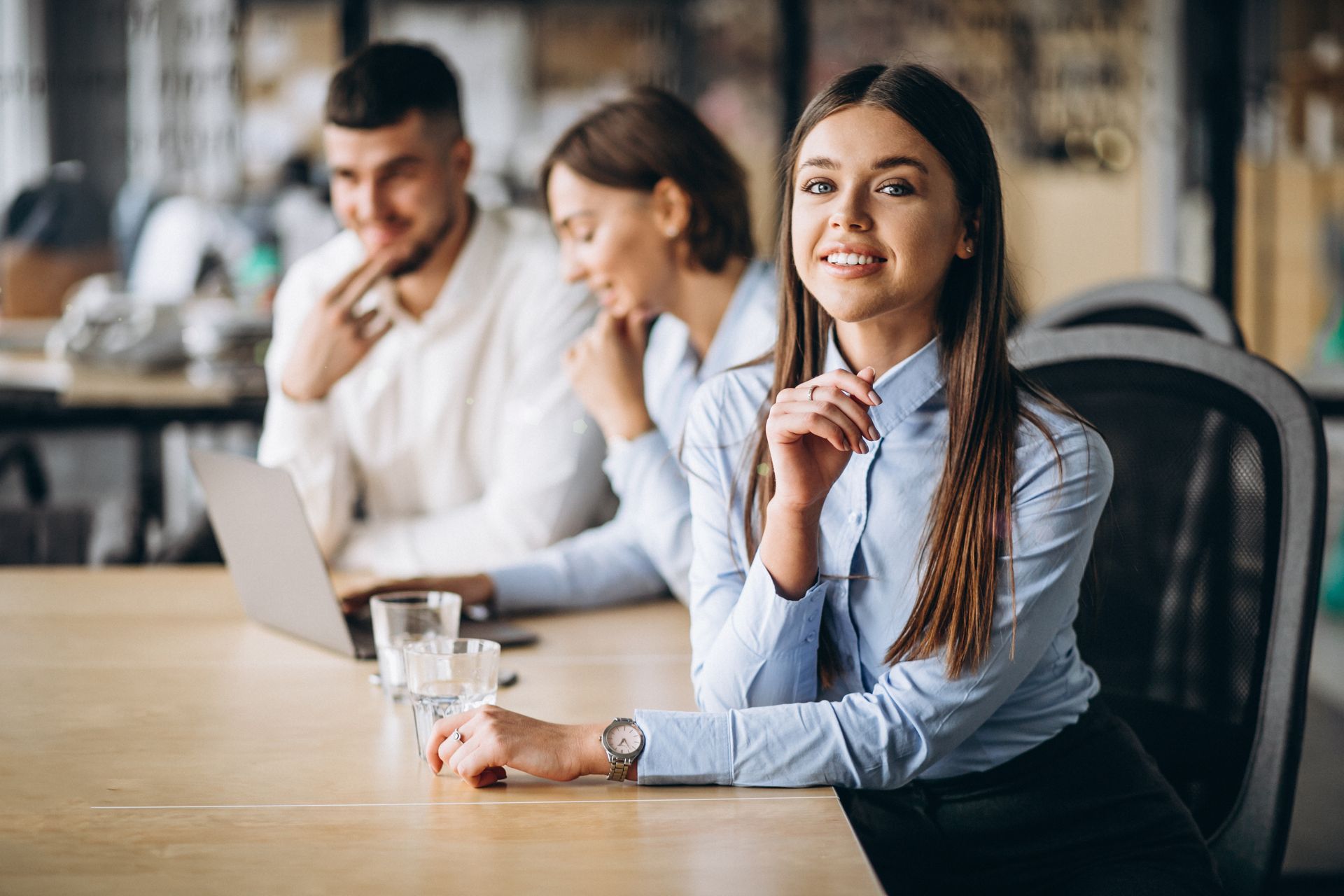A group of business people are sitting at a table looking at papers and a calculator.
