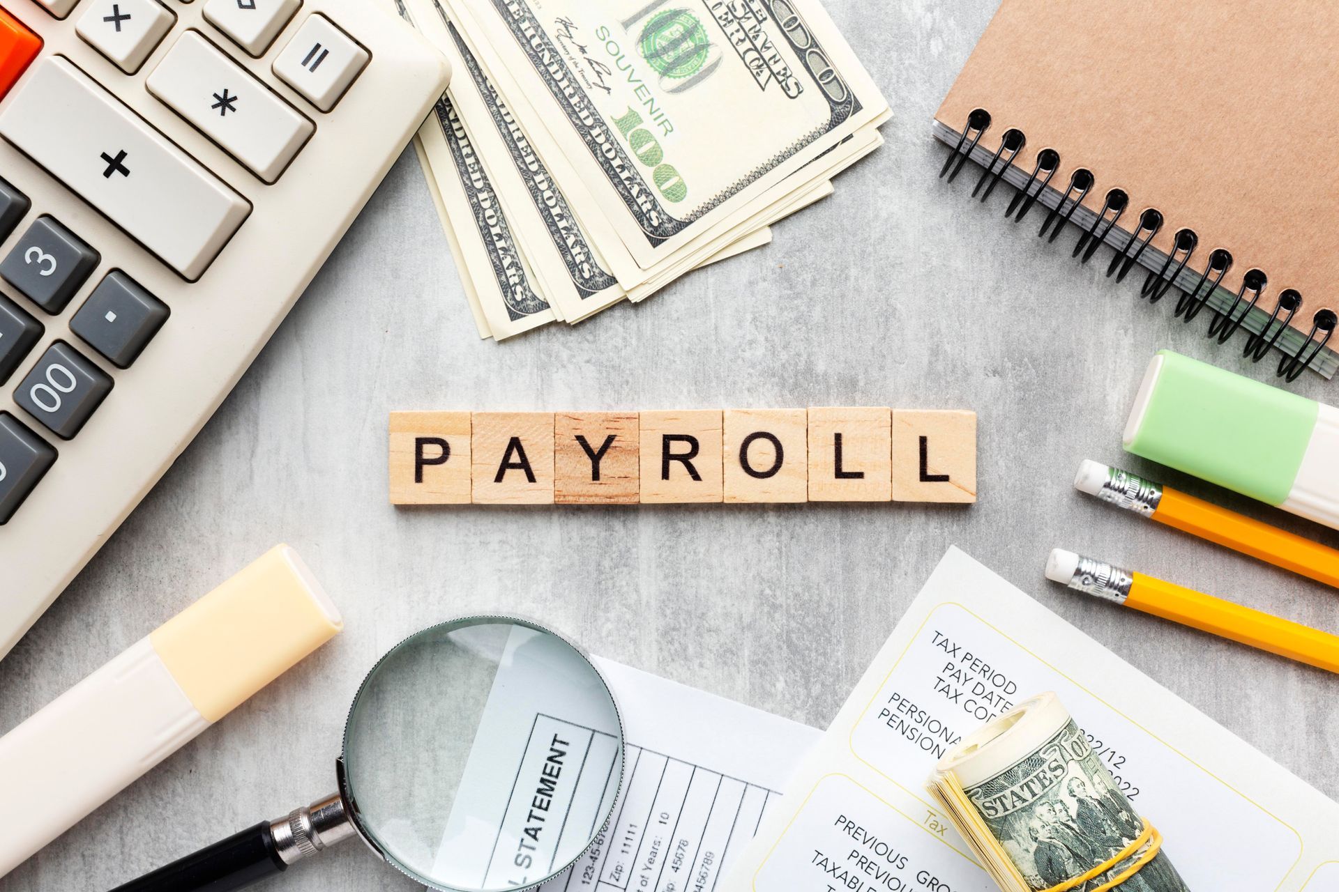 Payroll accounting tools: calculator, money, notepad, eraser, pencil, magnifying glass, and word 