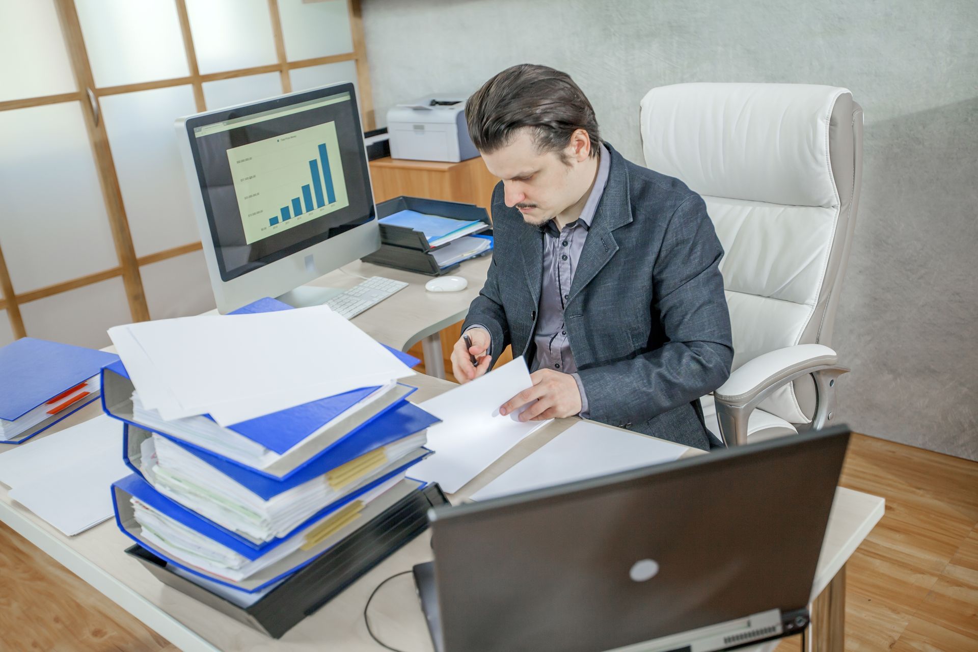 A man is sitting at a desk with a laptop and a computer.