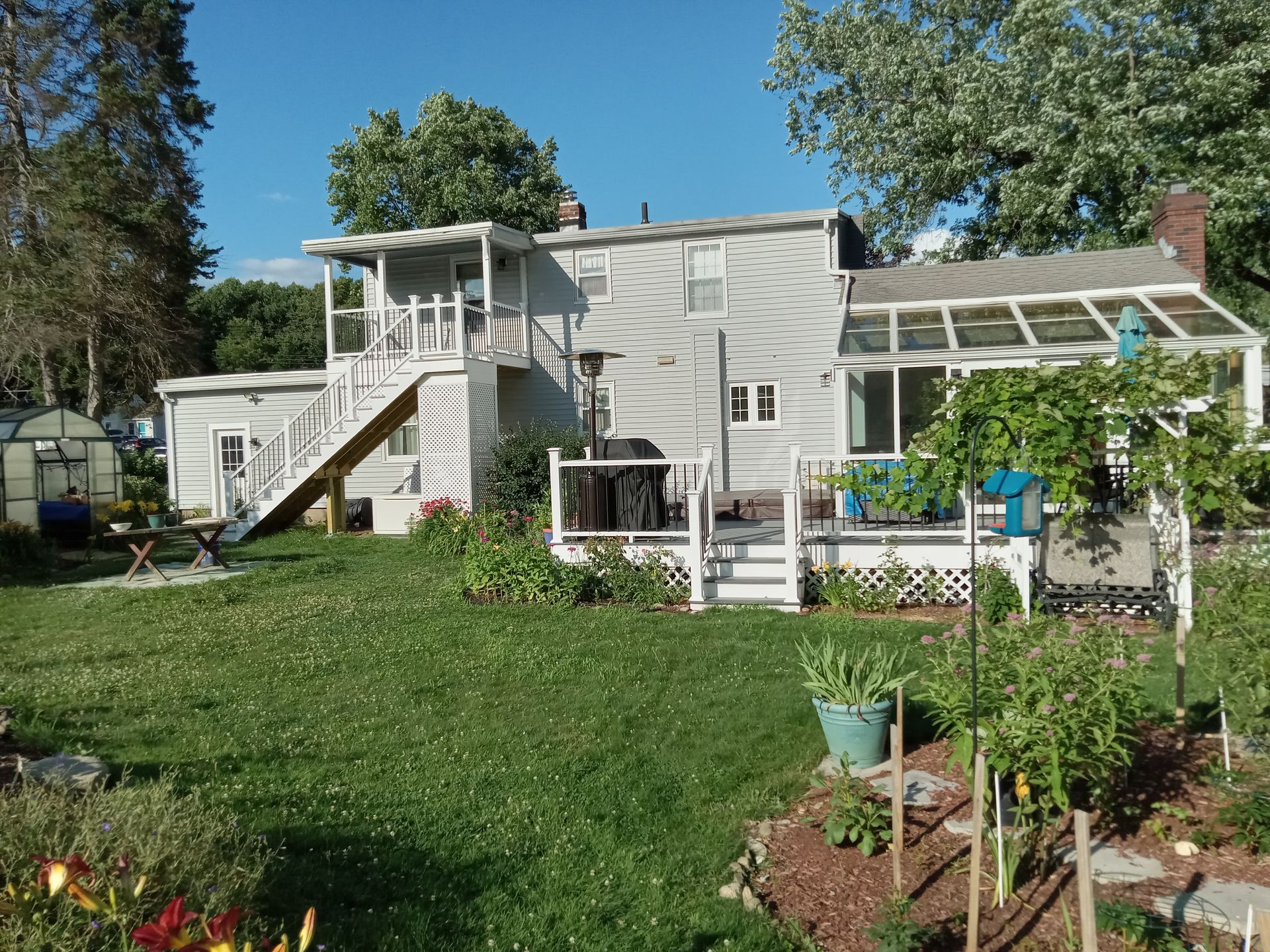 A large white house with a greenhouse in the backyard
