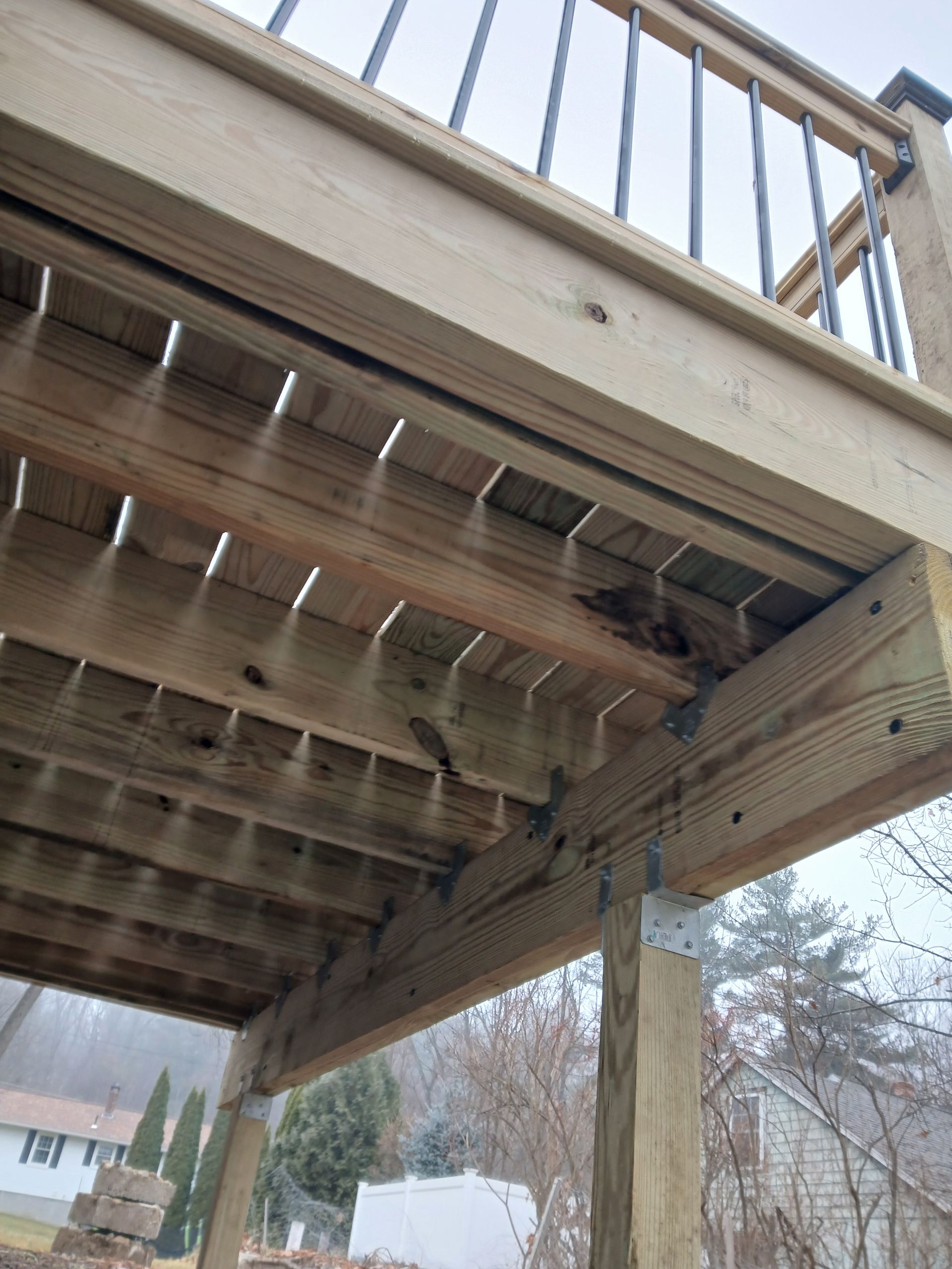 The bottom of a wooden deck with a metal railing