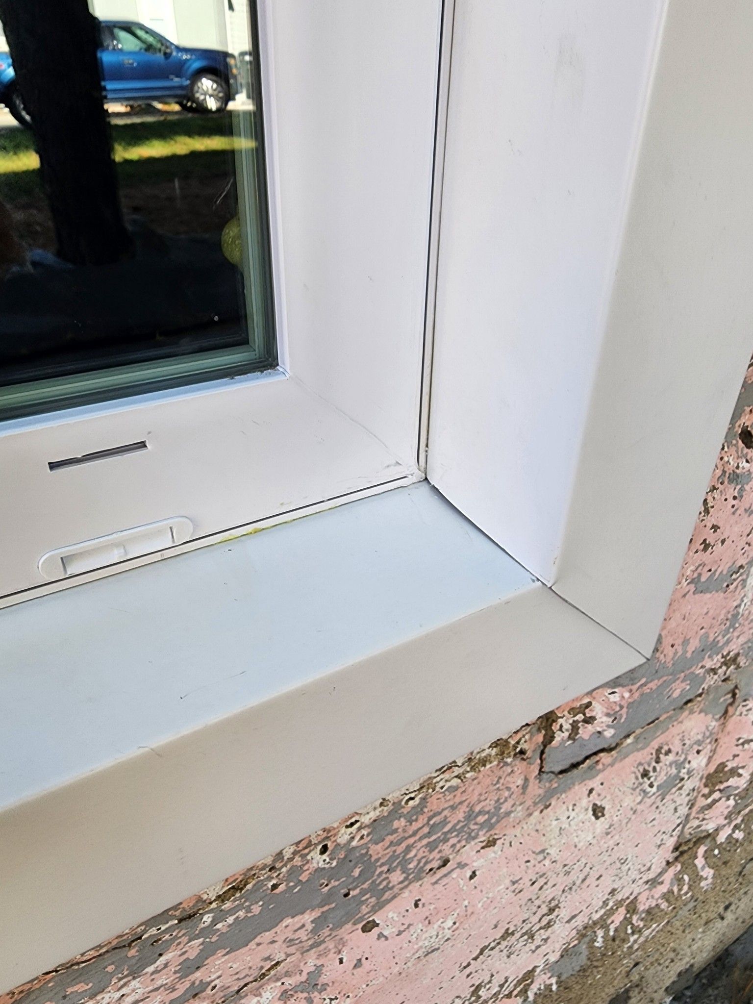 A close up of a window with a white trim on a pink wall.