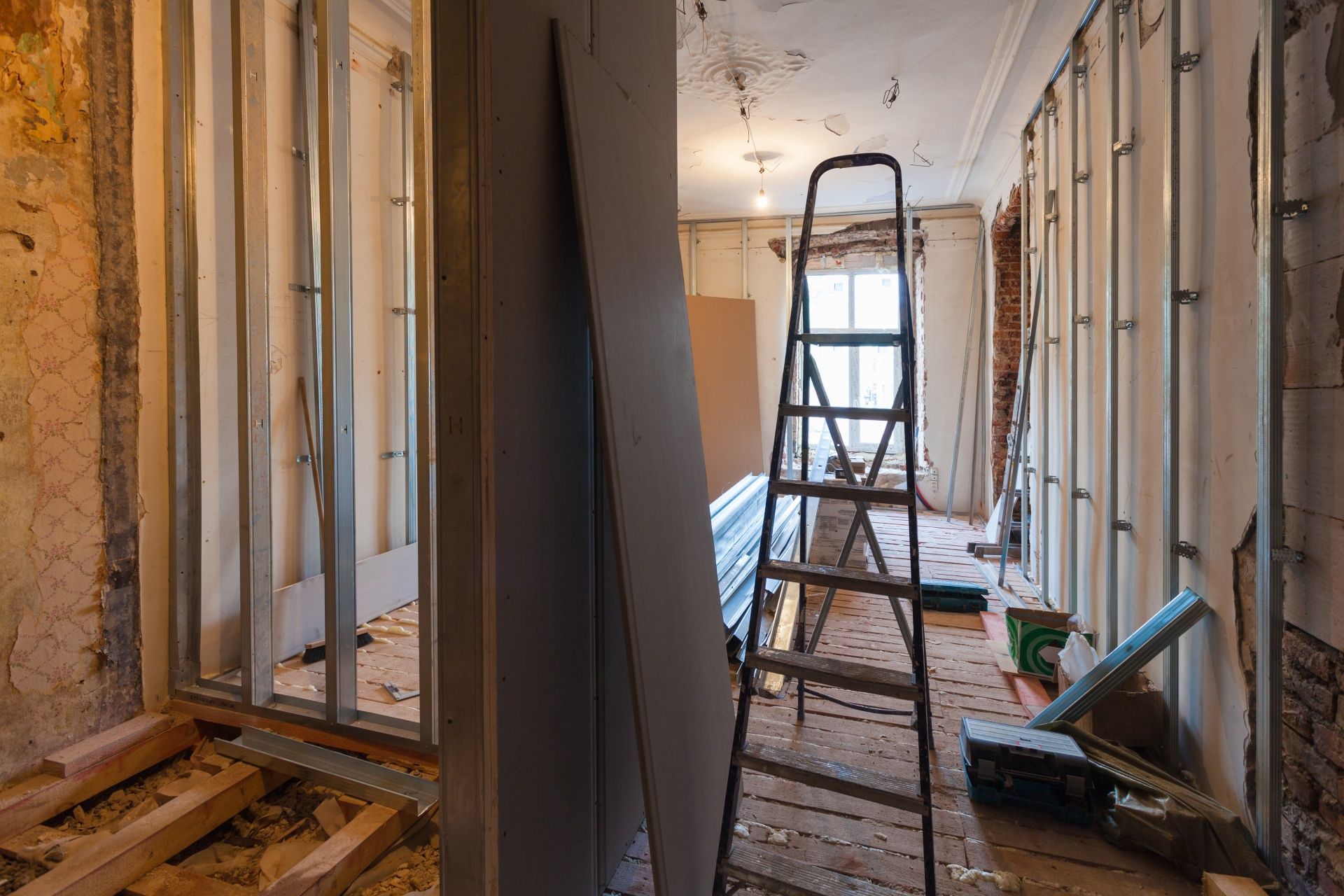 A ladder is sitting in the middle of a room under construction.