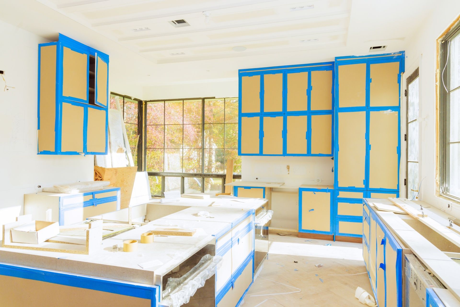 A kitchen under construction with blue cabinets and yellow cabinets.