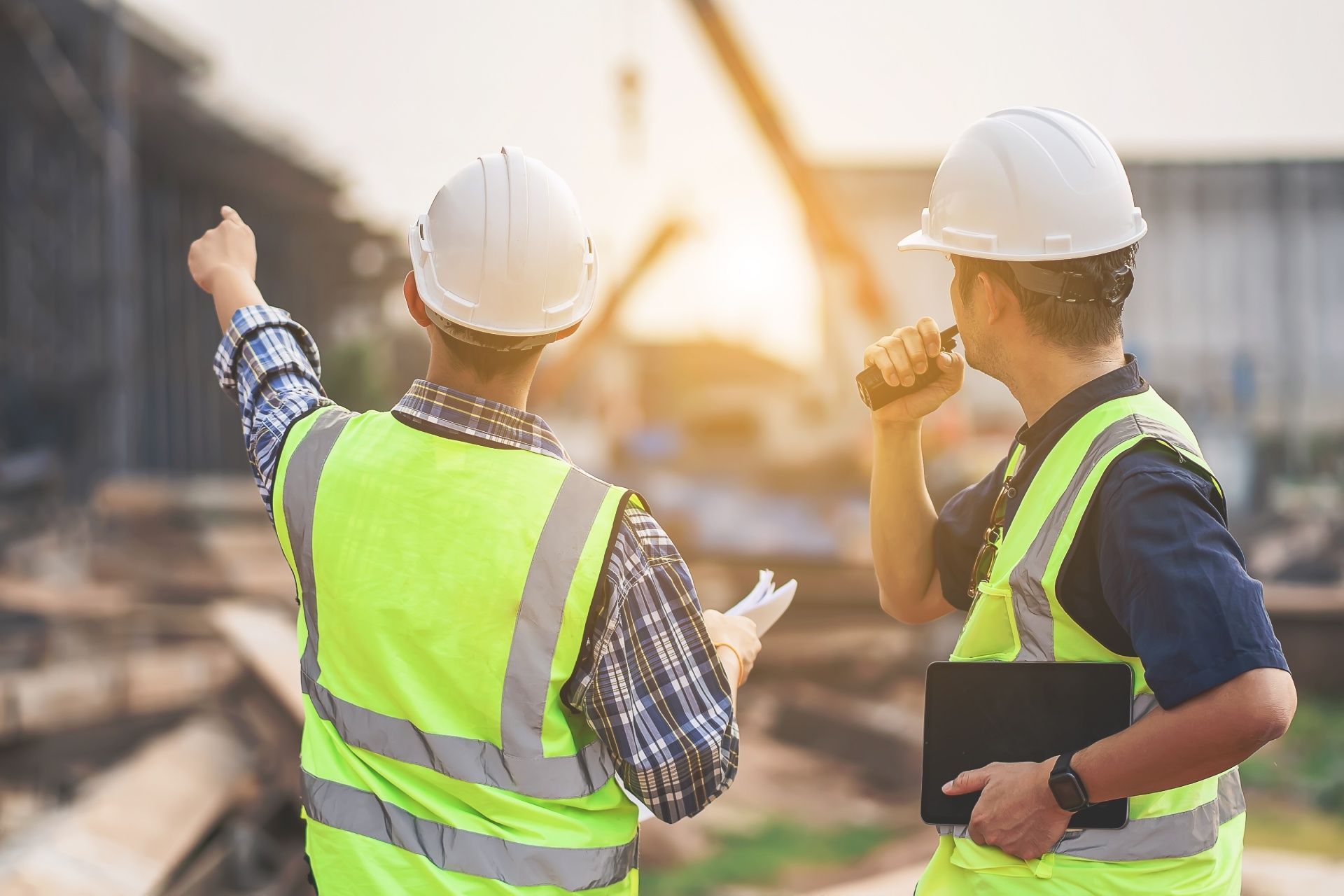 Two construction workers are standing next to each other on a construction site.