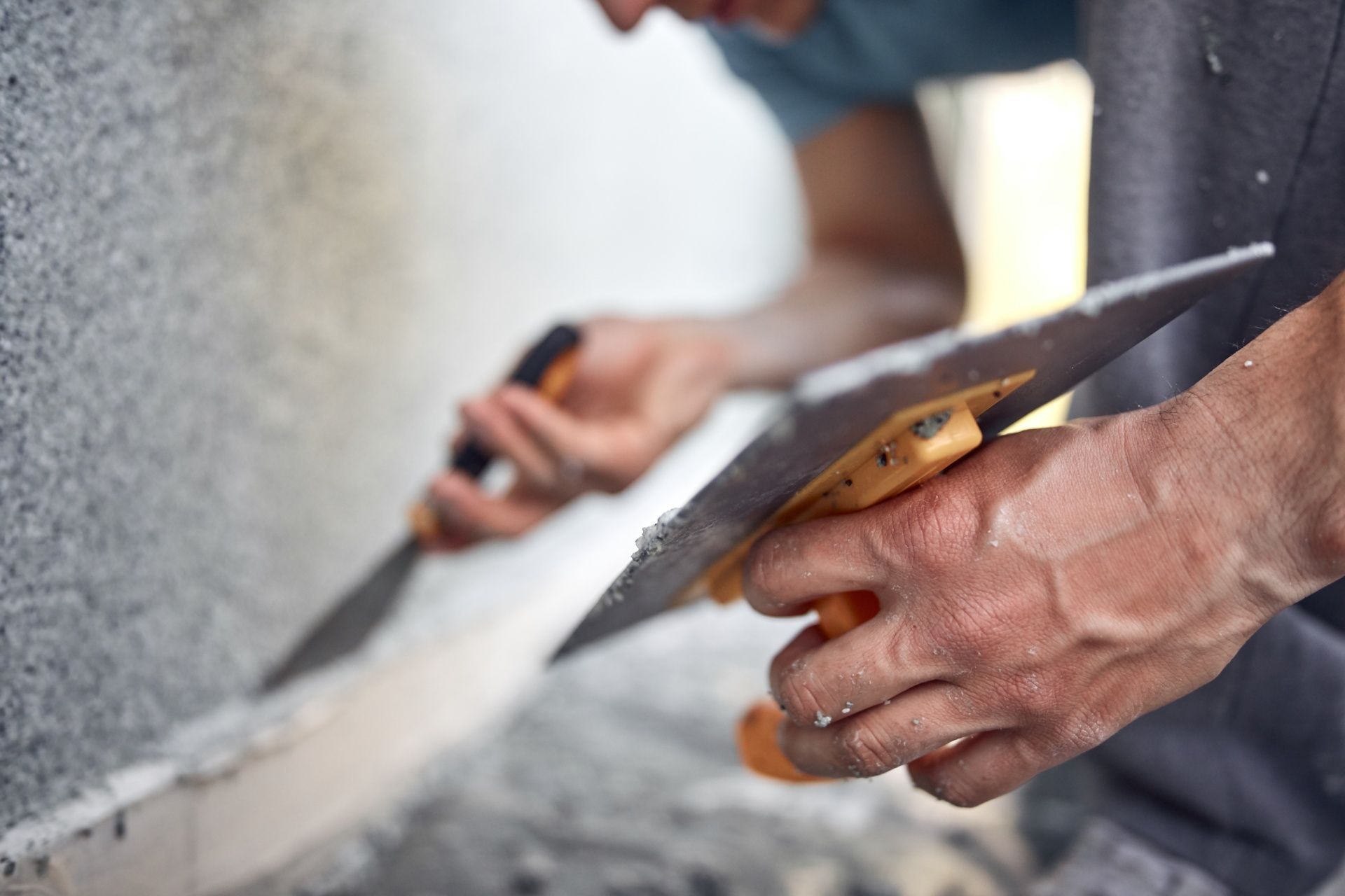 A man is cutting a piece of wood with a pair of scissors.
