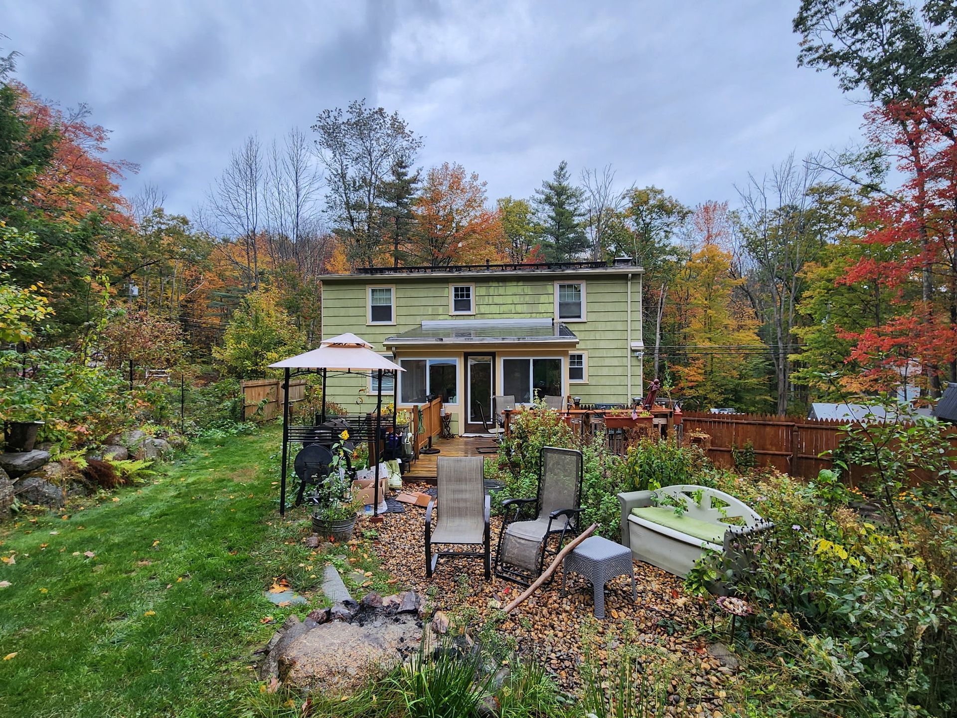 A house in the middle of a forest with a hot tub in the backyard.