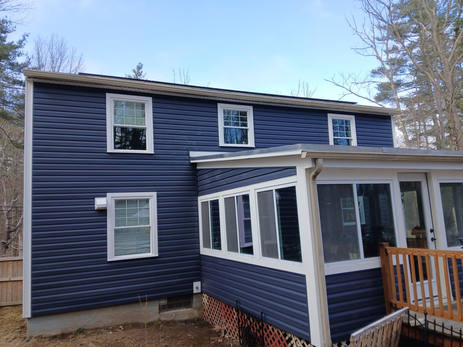 A blue house with white windows and a screened in porch