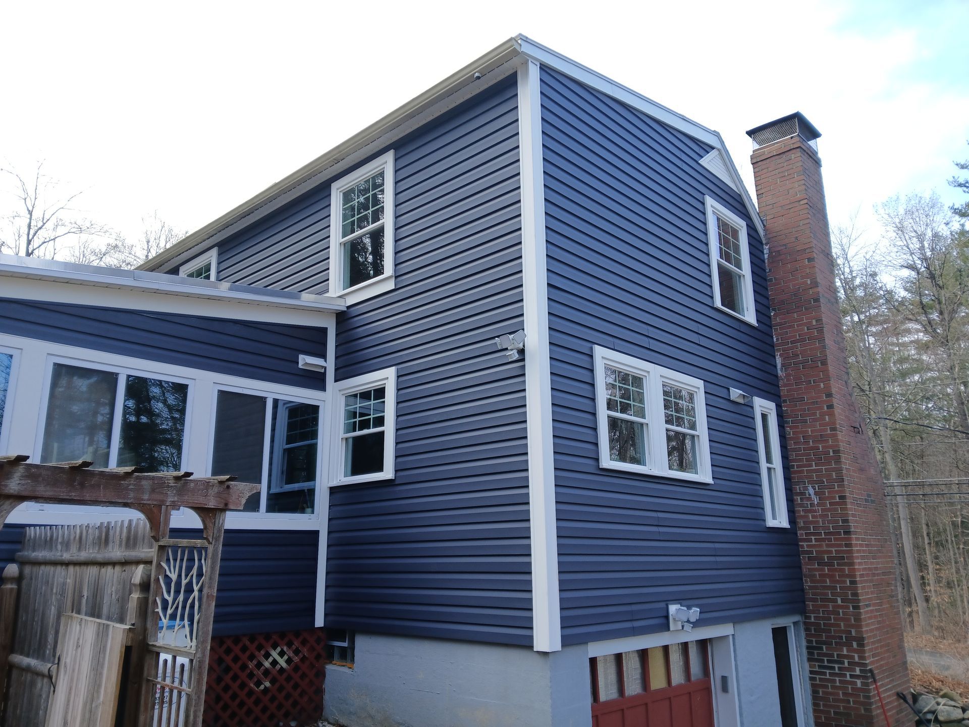 A blue house with white trim and a brick chimney