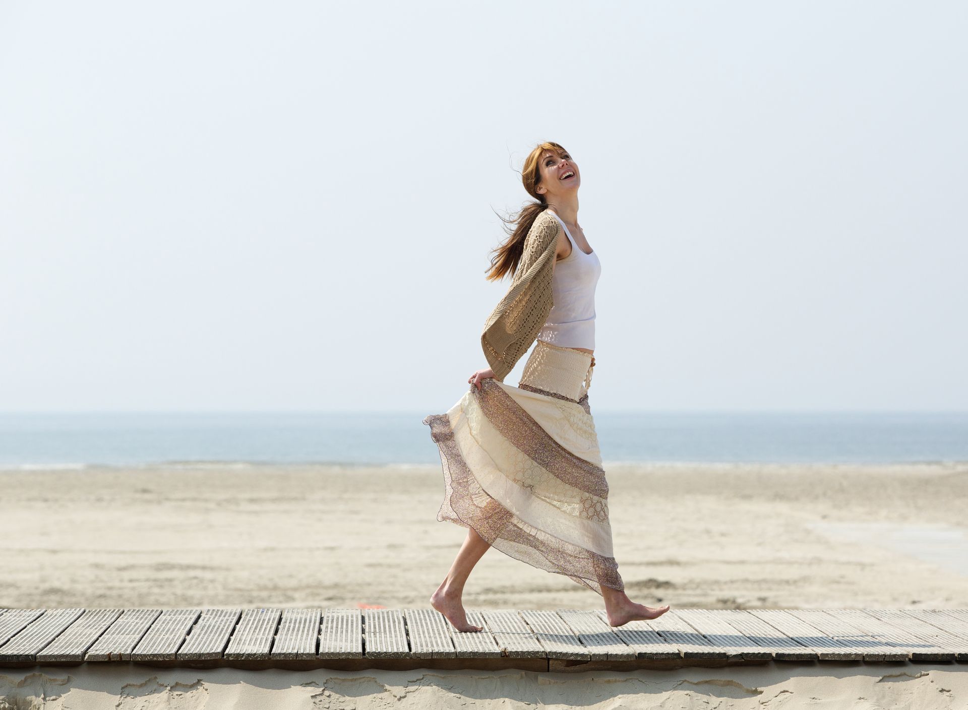 a woman is walking barefoot on a boardwalk on the beach