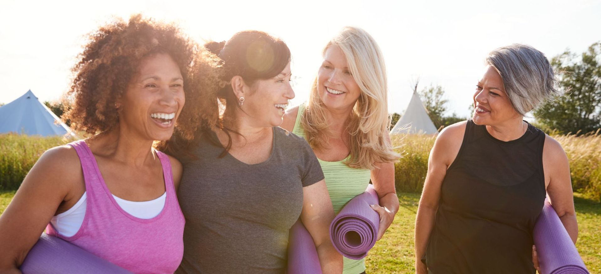 a group of women are holding yoga mats and smiling