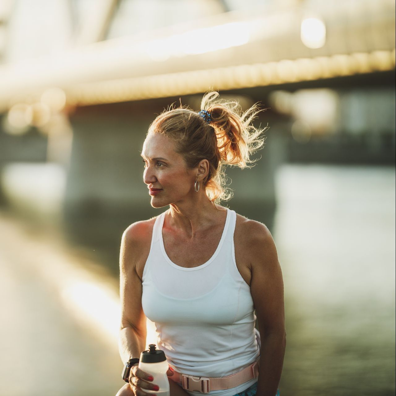 a woman in a white tank top is holding a water bottle
