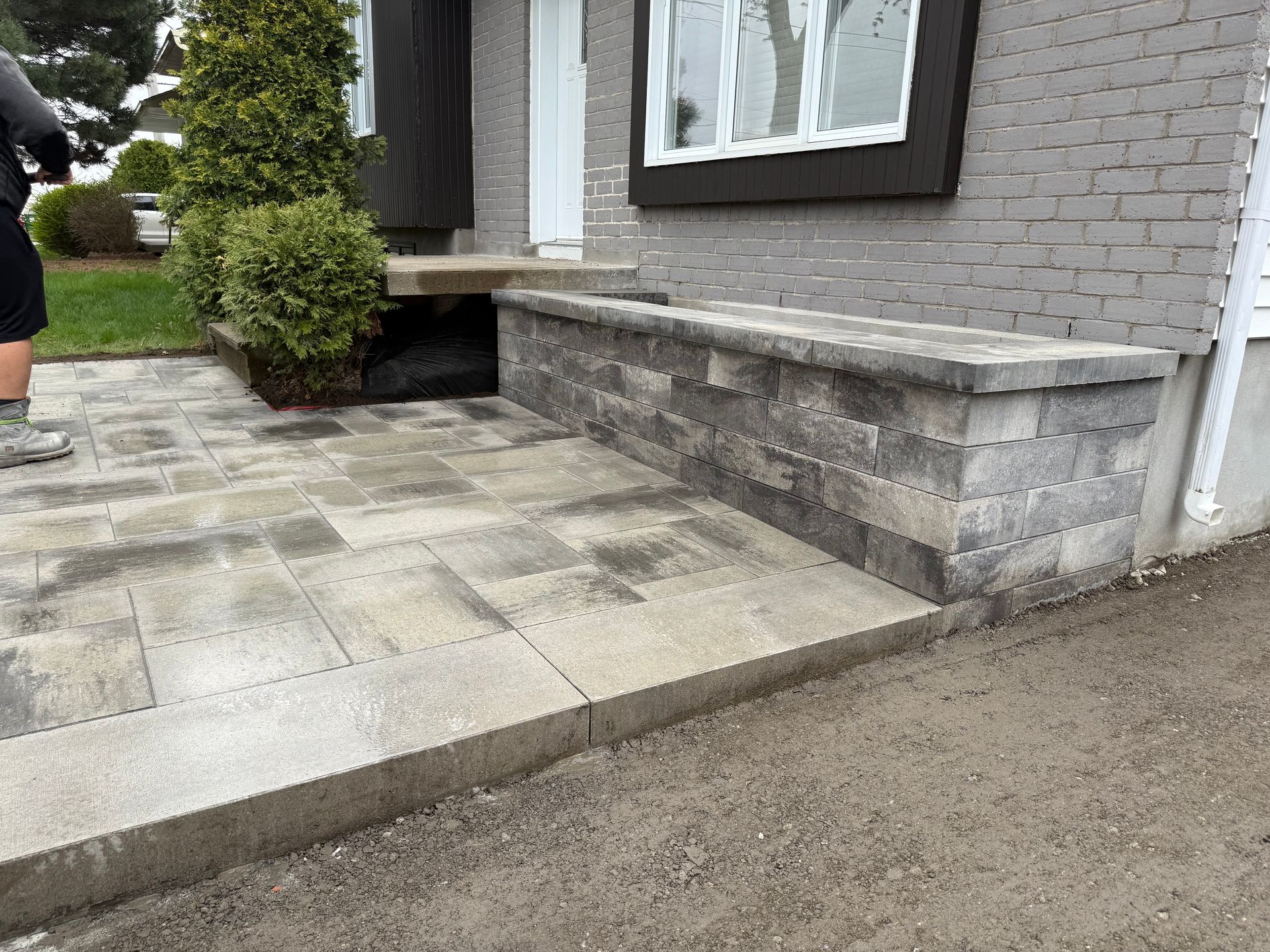 Stone patio and retaining wall with a ramp, next to a brick building.