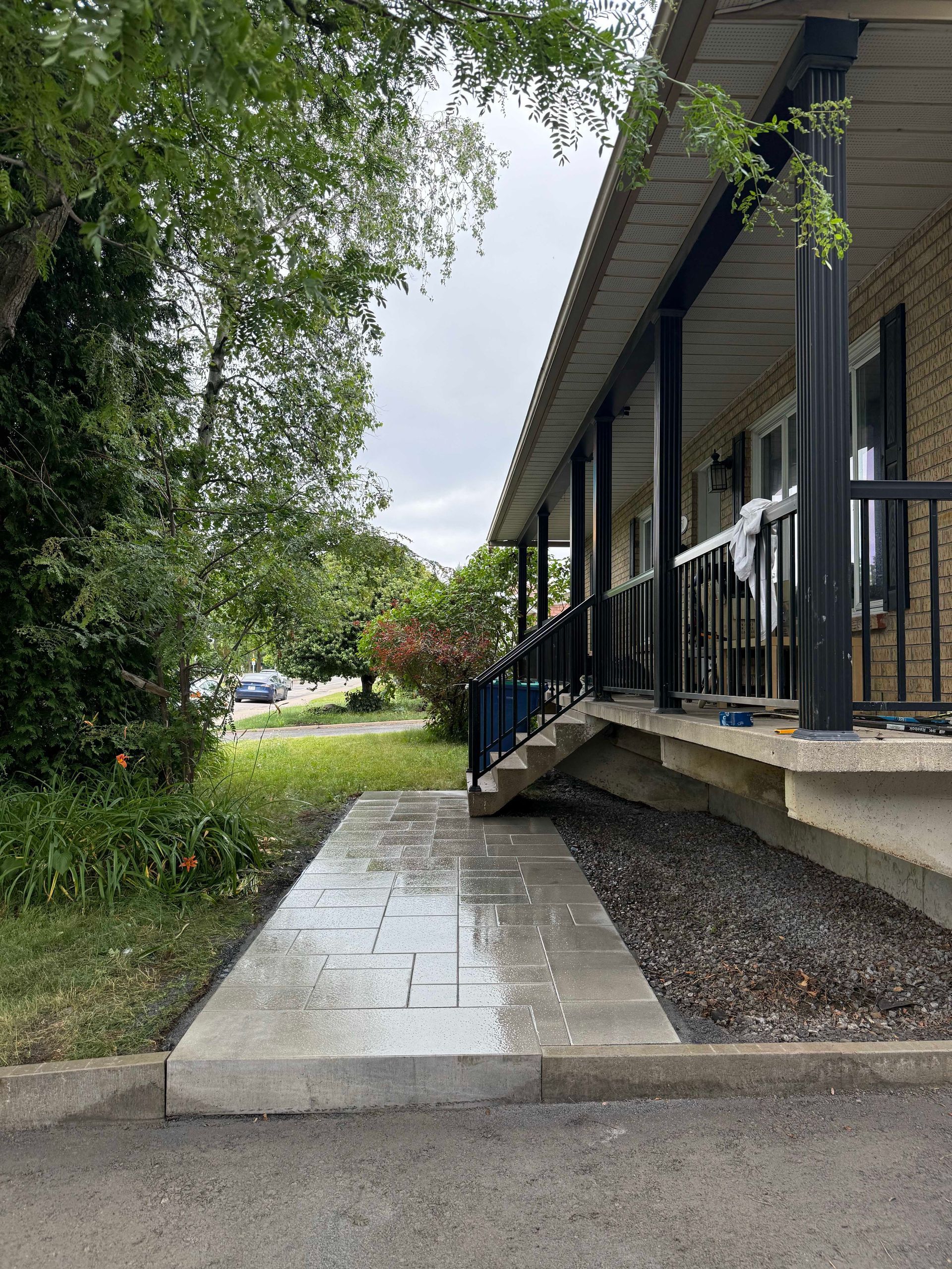 Concrete walkway leading to a building with a covered porch. Overcast day.