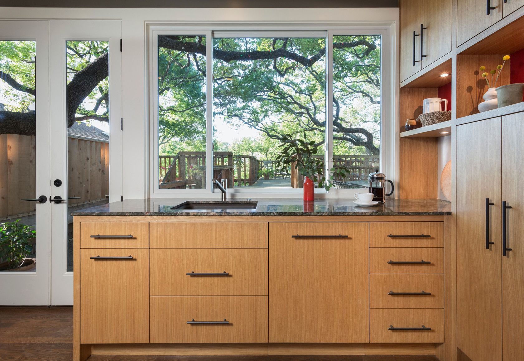 A kitchen with wooden cabinets , a sink , and a large window.