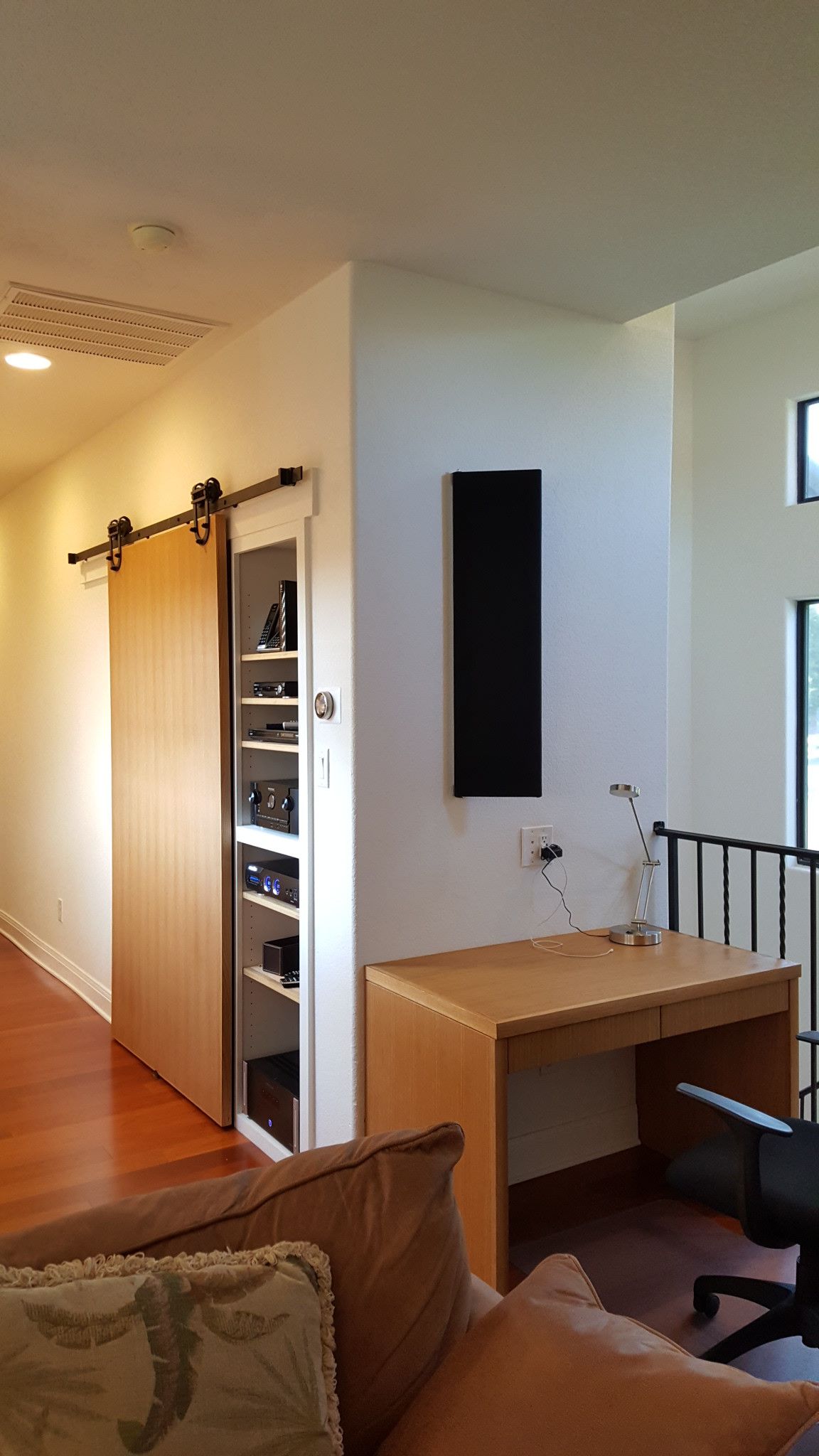 A living room with a sliding barn door and a desk.