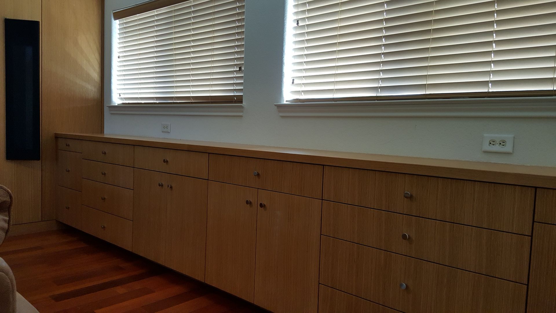 A living room with wooden cabinets and blinds on the windows.