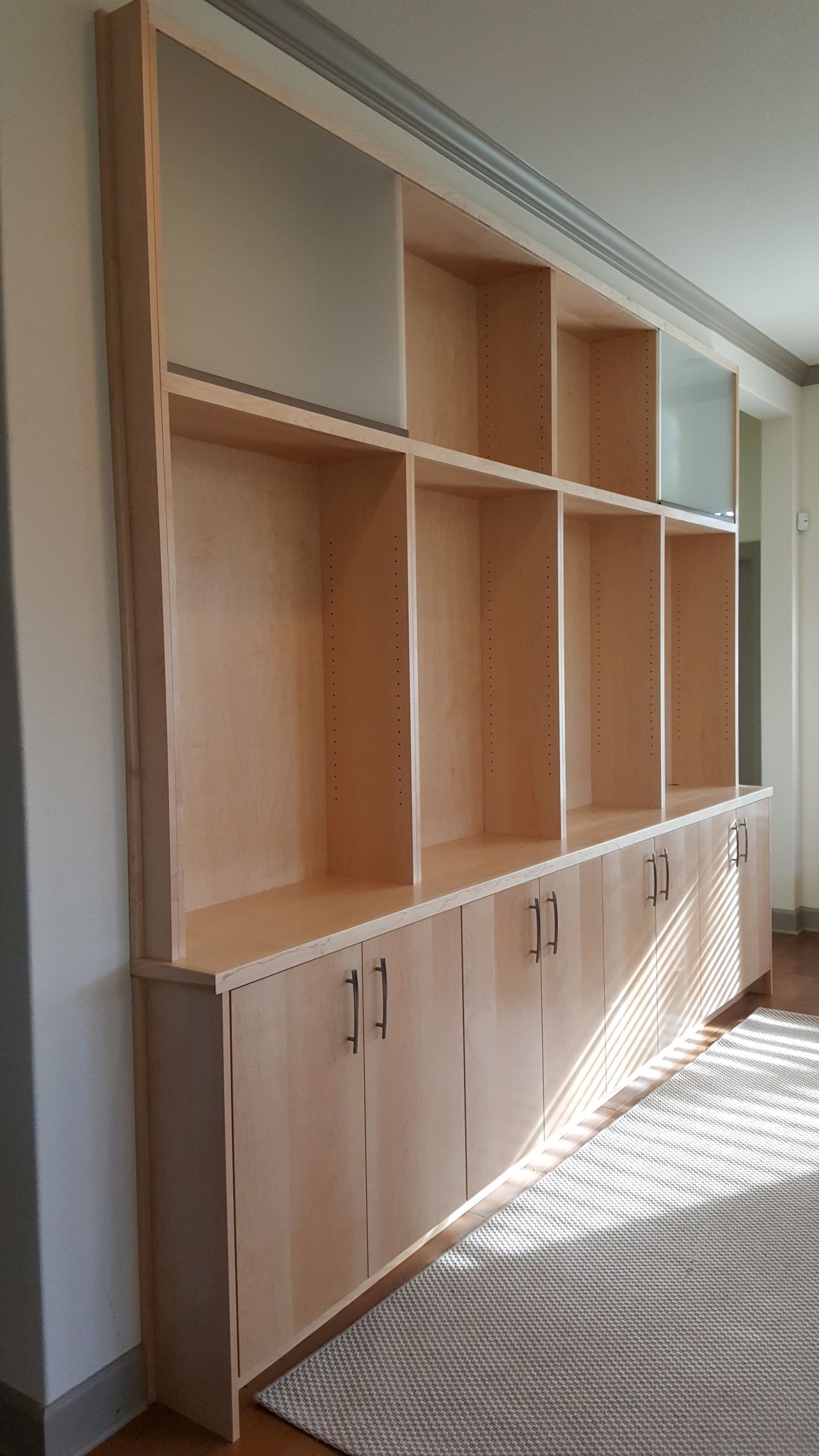 A living room with a large wooden bookshelf and cabinets.