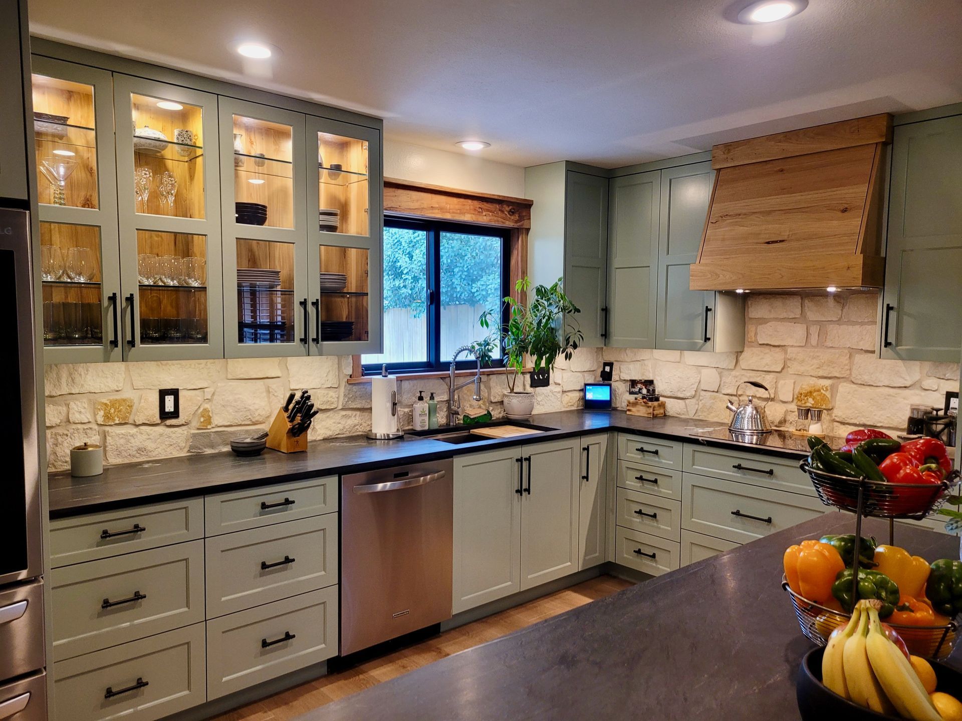A kitchen with green cabinets and stainless steel appliances