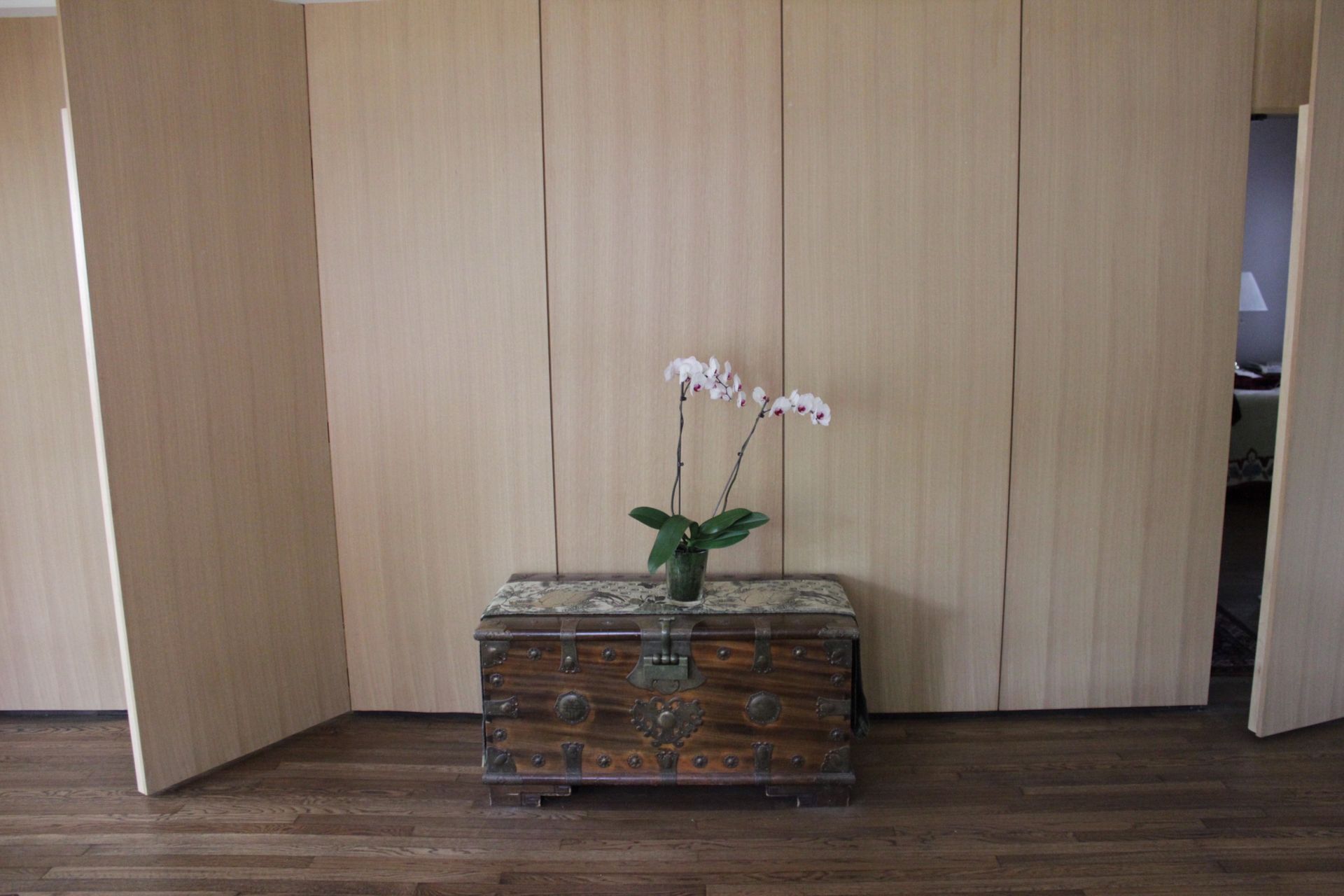 A vase of flowers is sitting on a wooden chest in a room.