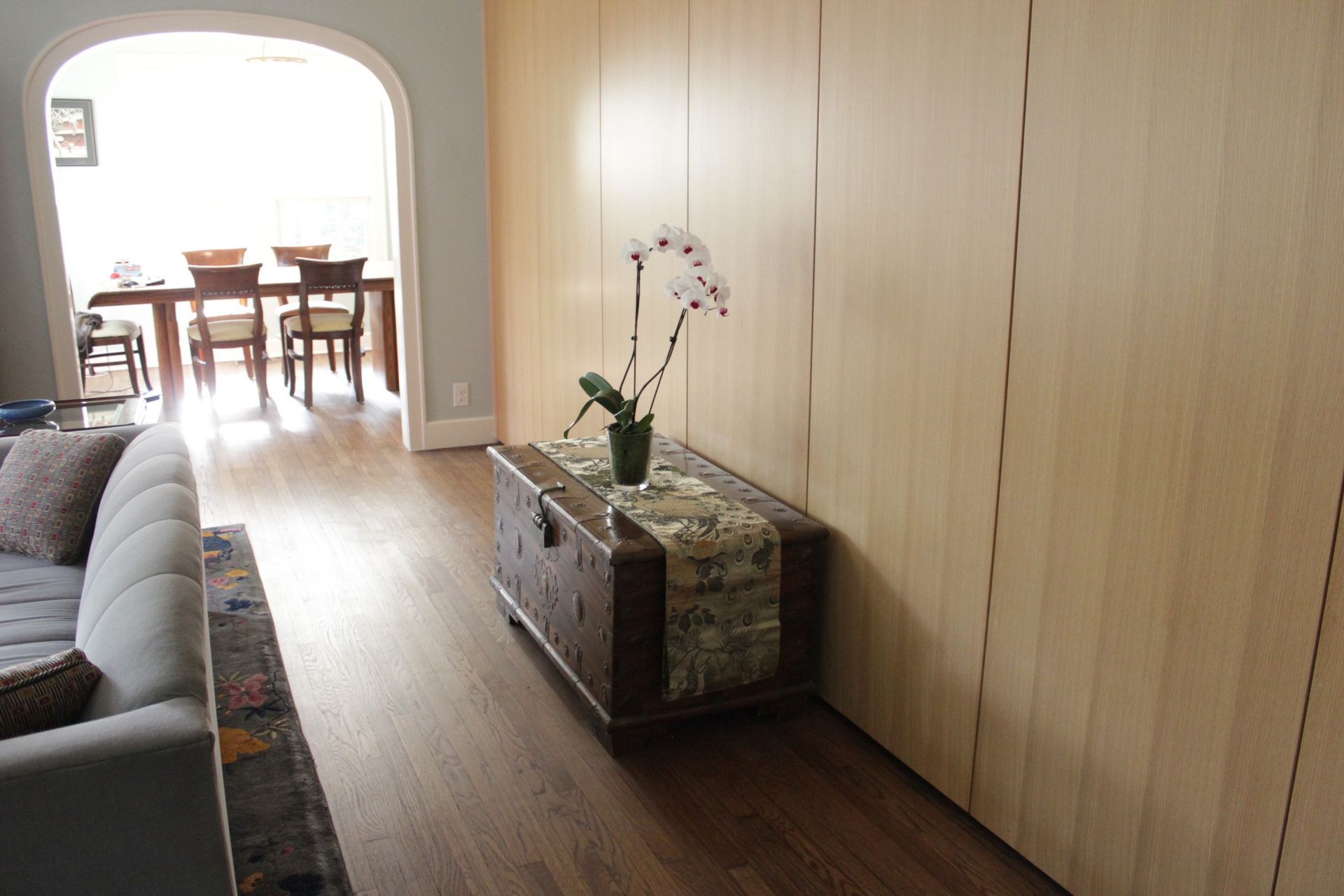 A living room with a couch and a trunk with a vase of flowers on it.