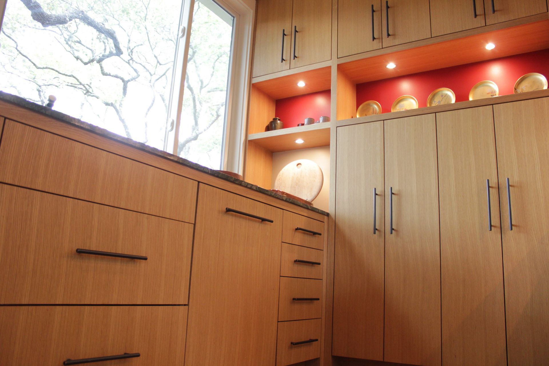 A kitchen with wooden cabinets and drawers and a window