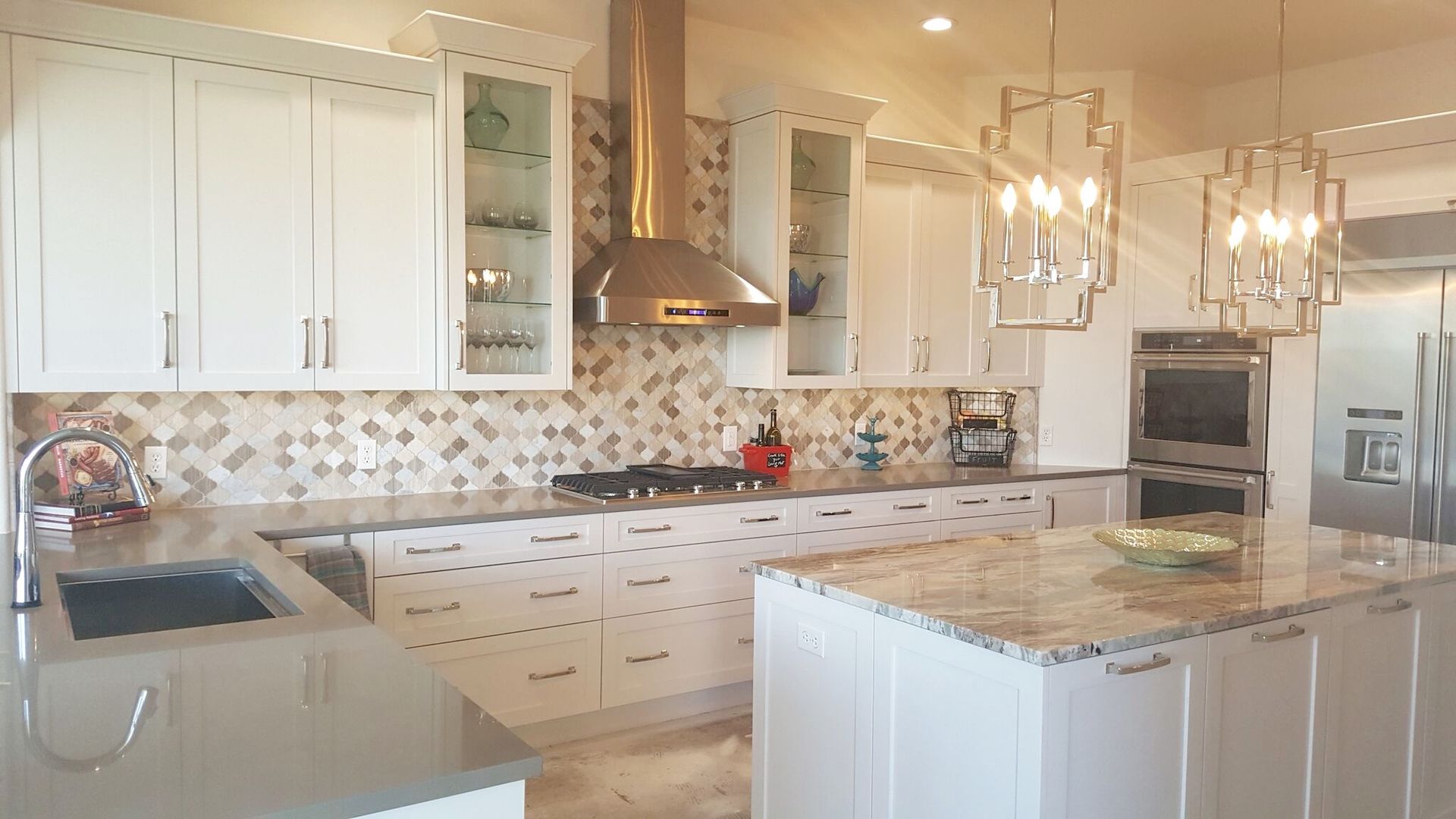 A kitchen with white cabinets , granite counter tops , stainless steel appliances and a large island.