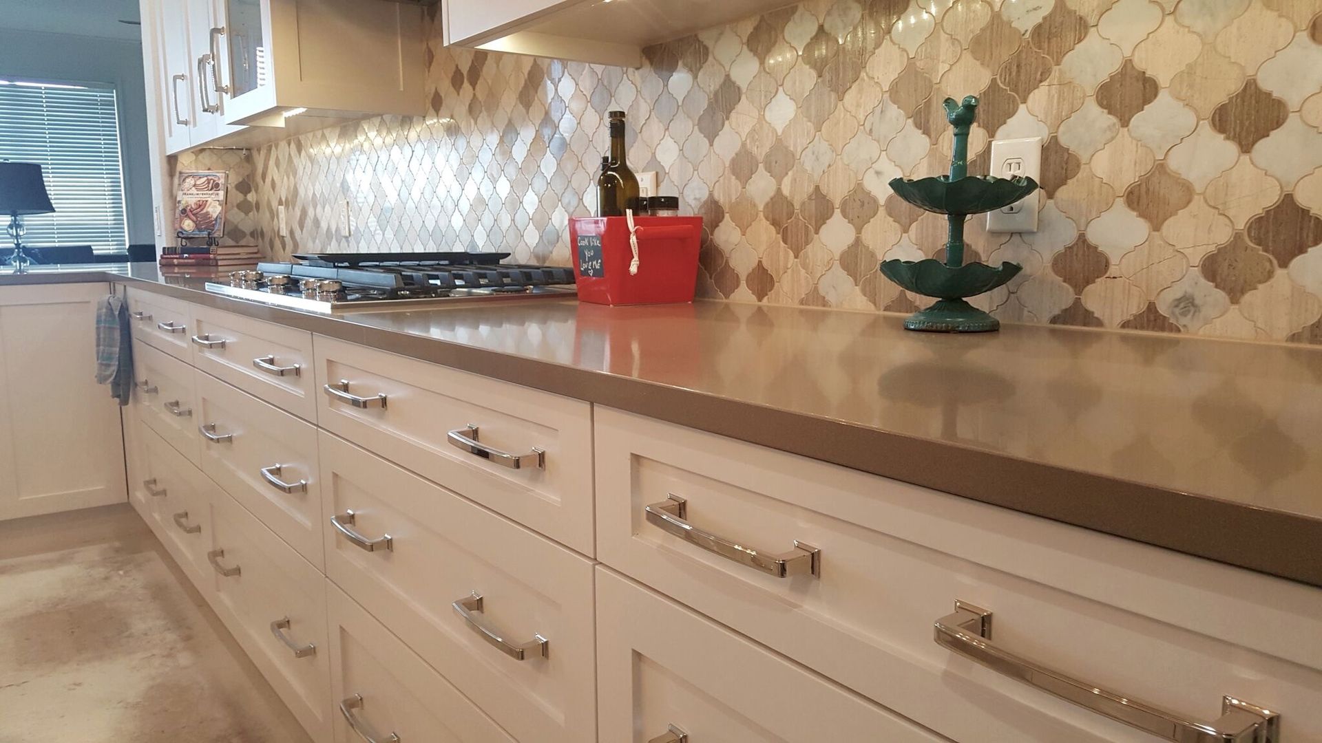 A kitchen with white cabinets and a bottle of wine on the counter.