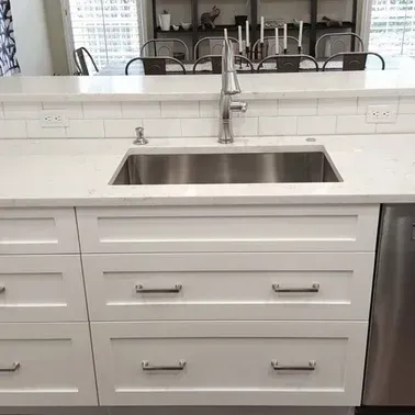 A kitchen with white cabinets and a stainless steel sink.